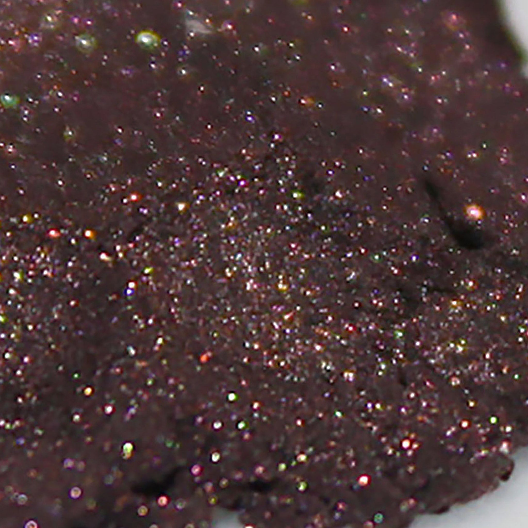 Side view of dark rose brown loose powder eyeshadow with shimmer particles in a compact jar