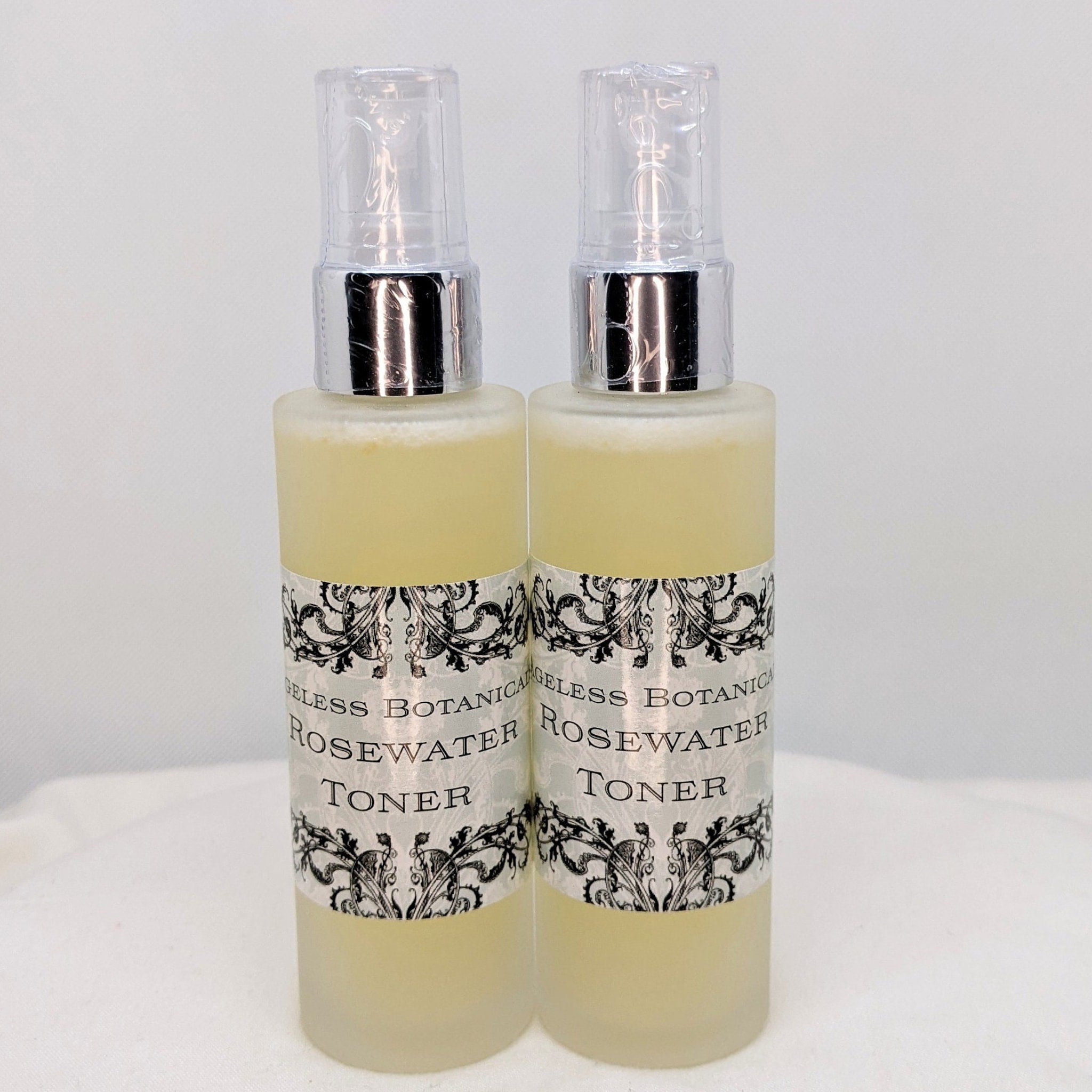 Rosewater toner bottles with clear spray tops, yellow liquid, and decorative labels.