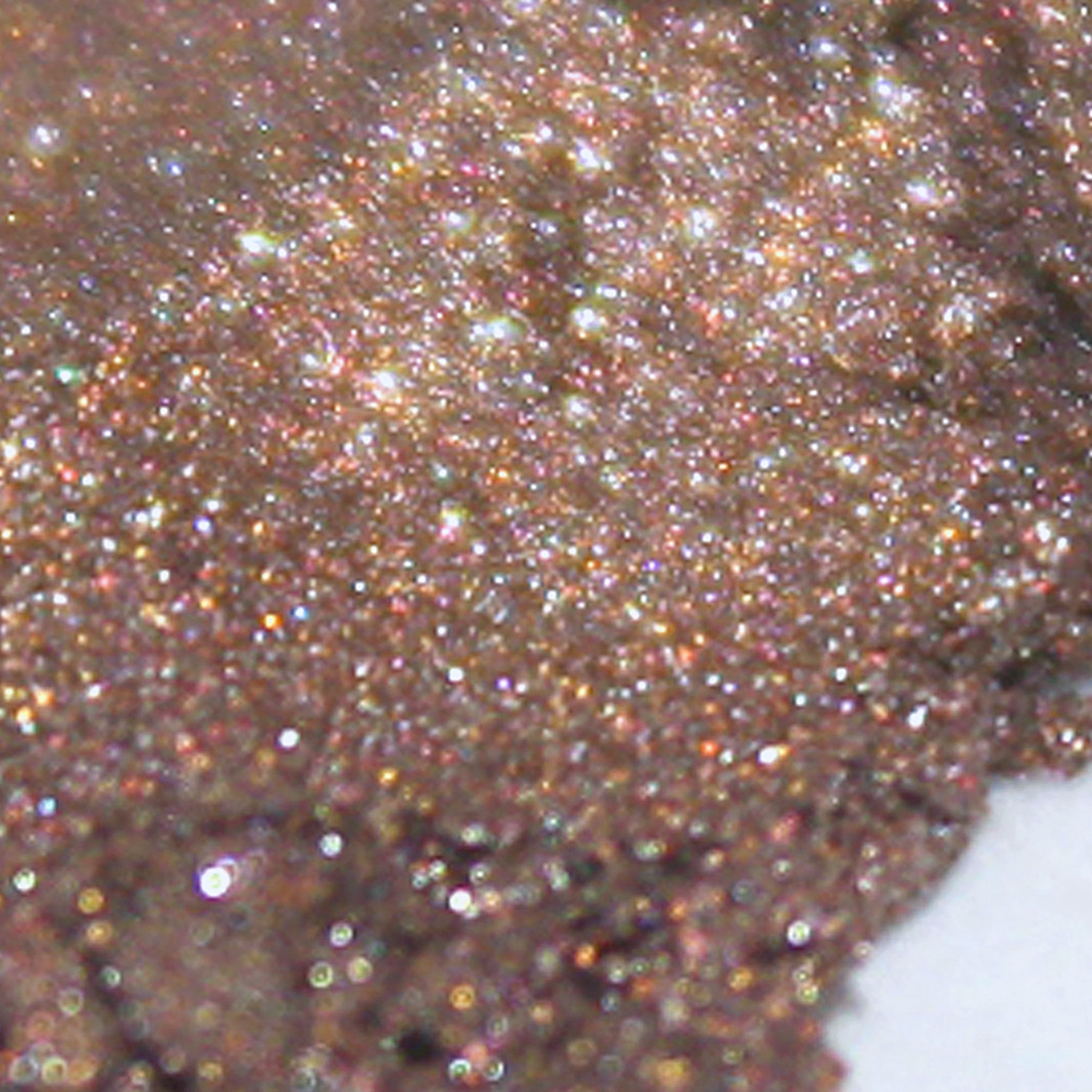Side view of loose metallic rose brown eye shadow powder in open jar with steampunk-inspired lid design