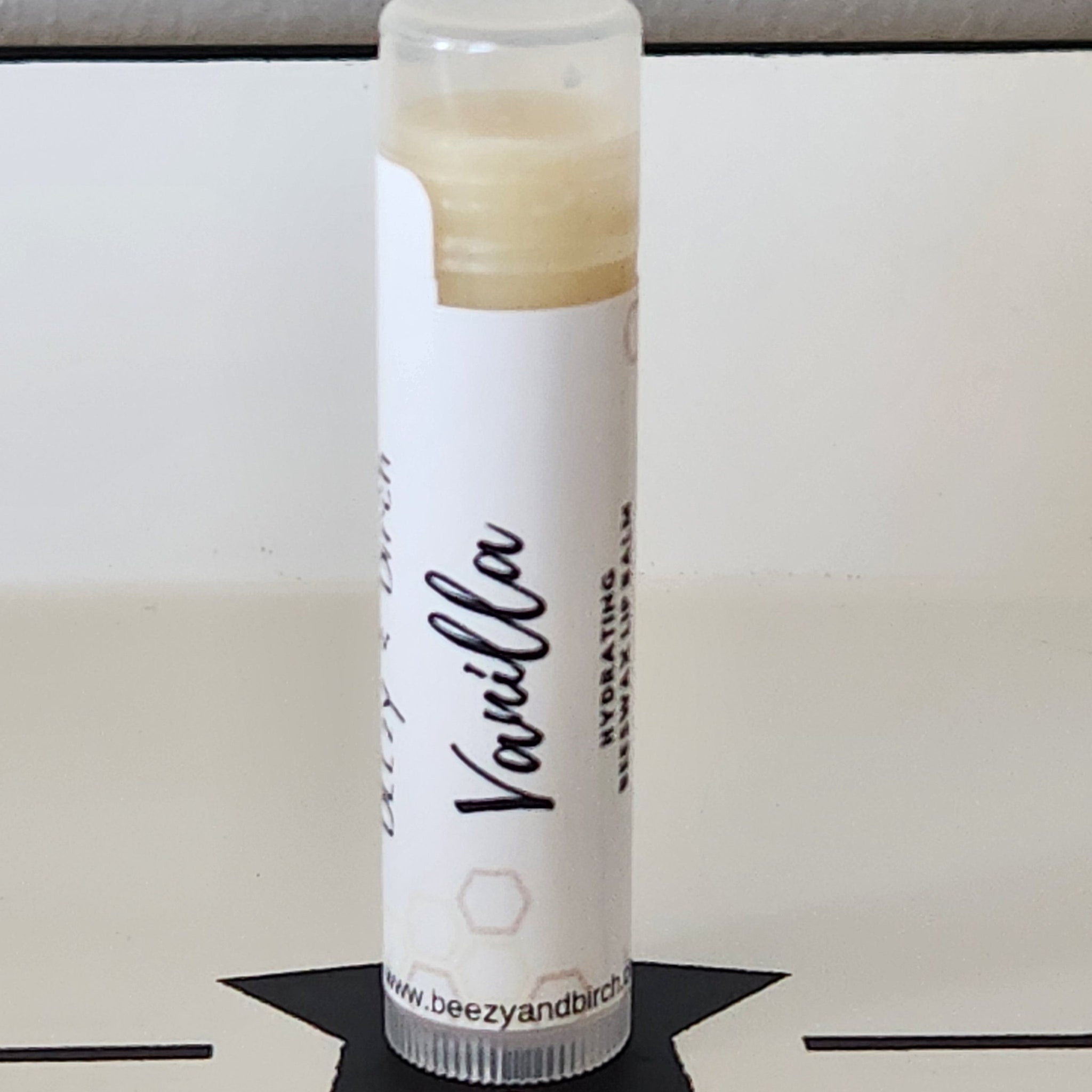 Lip balm tube with white label, vanilla text, and BEEzy & Birch branding