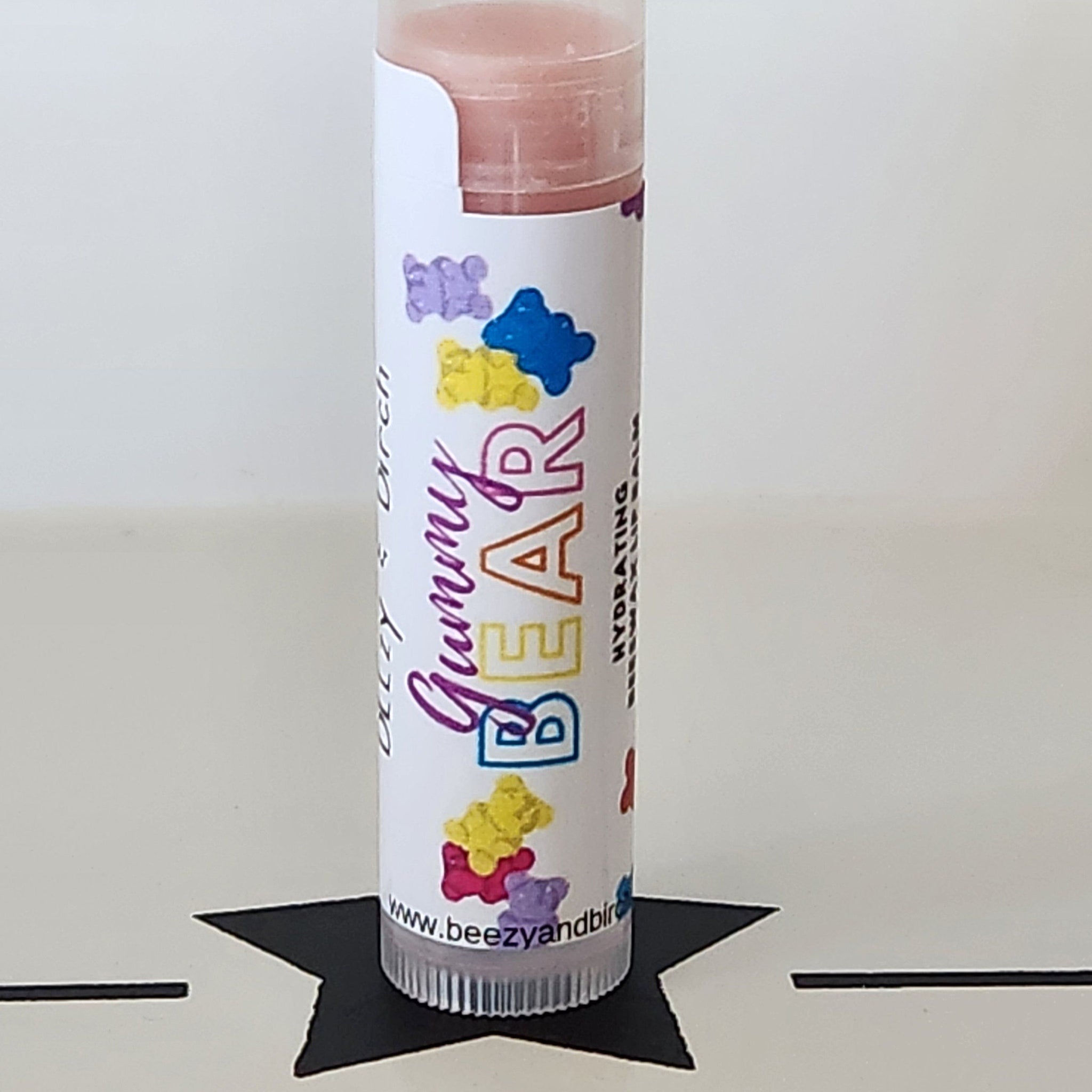Lip balm tube with white label, colorful gummy bear pattern, and BEEzy & Birch branding