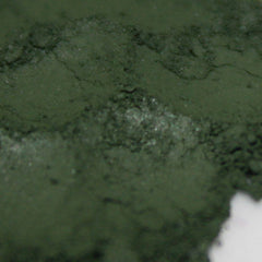 Side view of loose powder vegan matte eye shadow in deep moss green, showcasing fine pigment texture