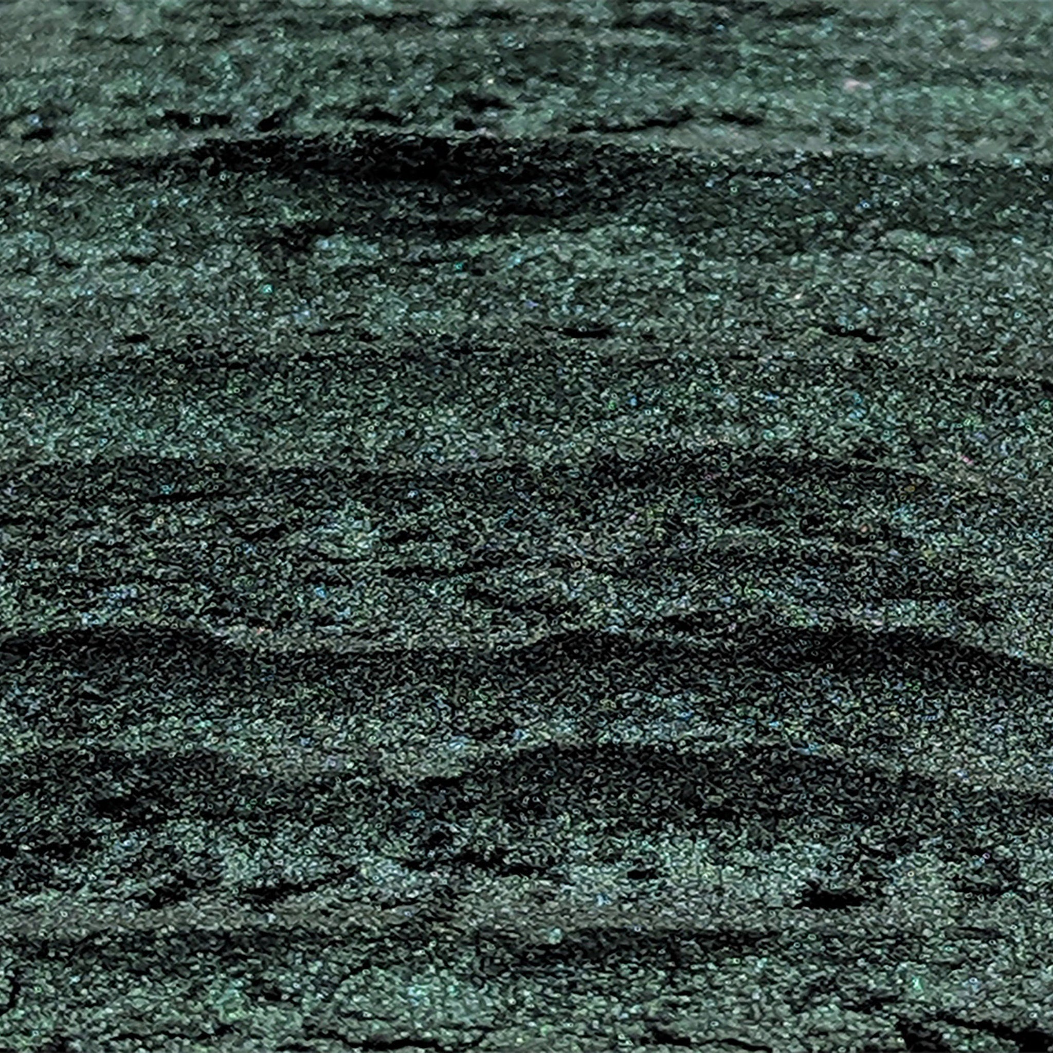 Hand applying deep emerald green shimmer eyeshadow with duochrome effect using a fluffy brush