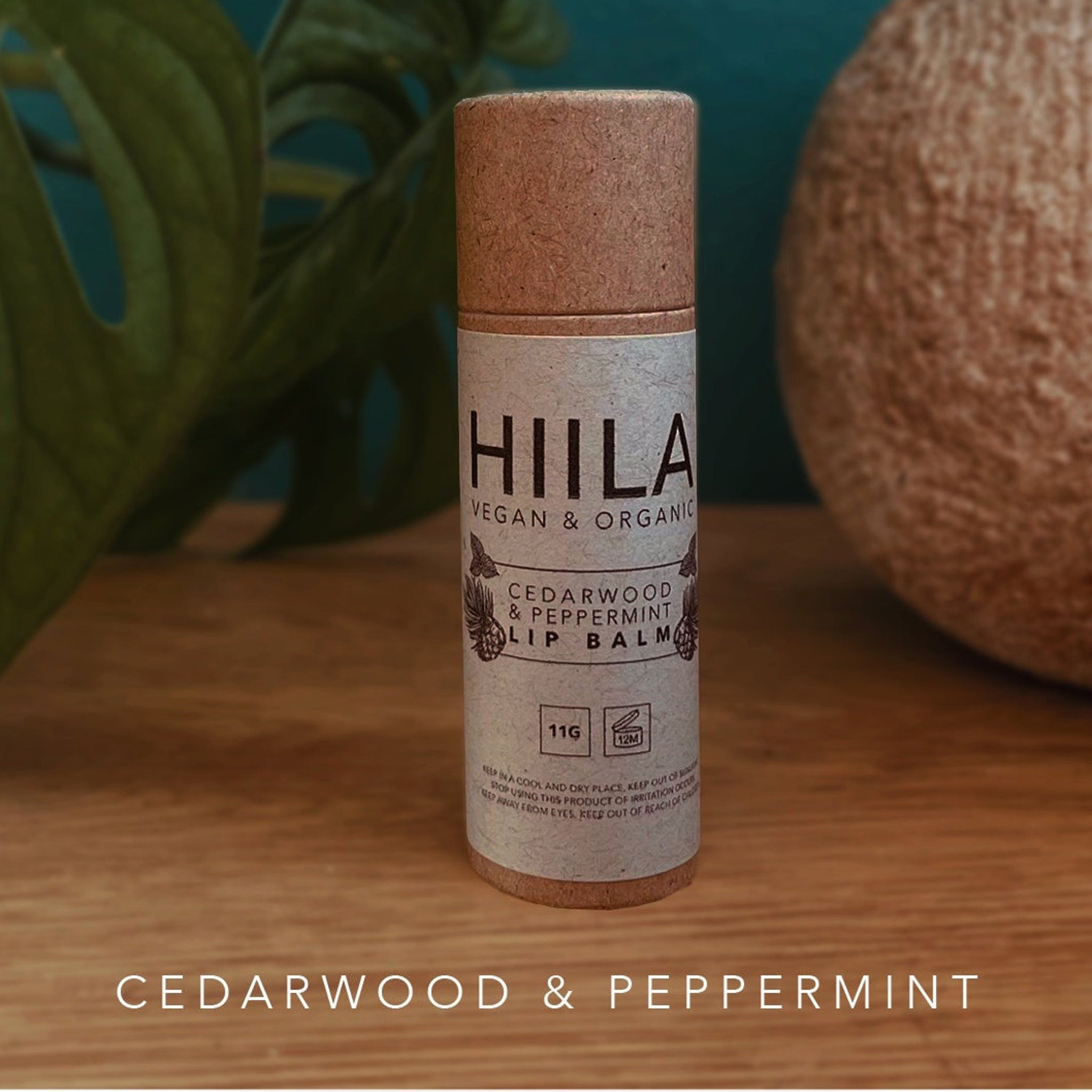 Lip balm tube with HIILA label, brown and beige, on wooden surface