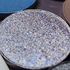 Close-up of 54 vibrant eye shadow pans showing matte, shimmer, and pressed pigment textures in a sleek black palette