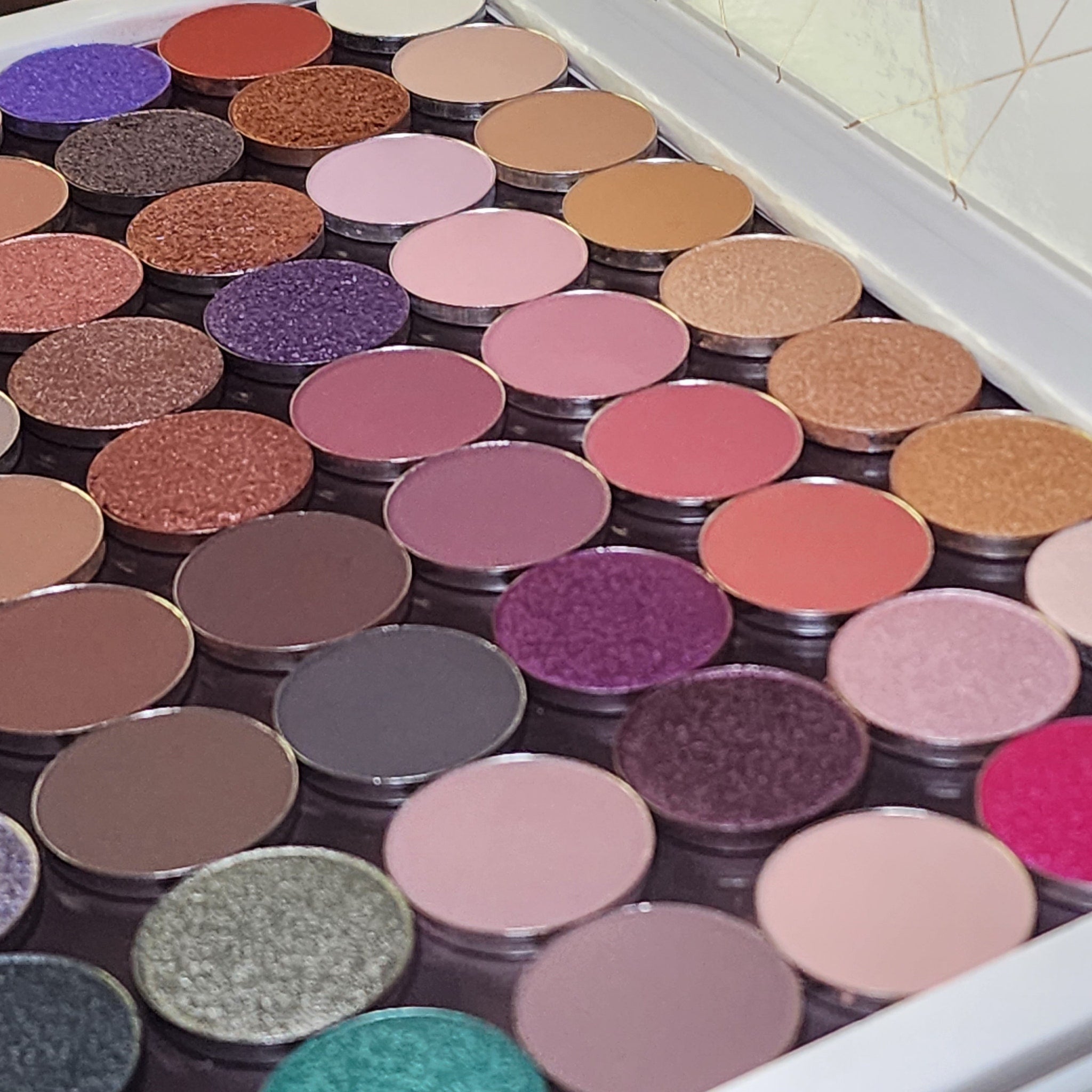 Open 54-pan eyeshadow palette displaying matte, shimmer, and pressed pigment squares in vibrant colors