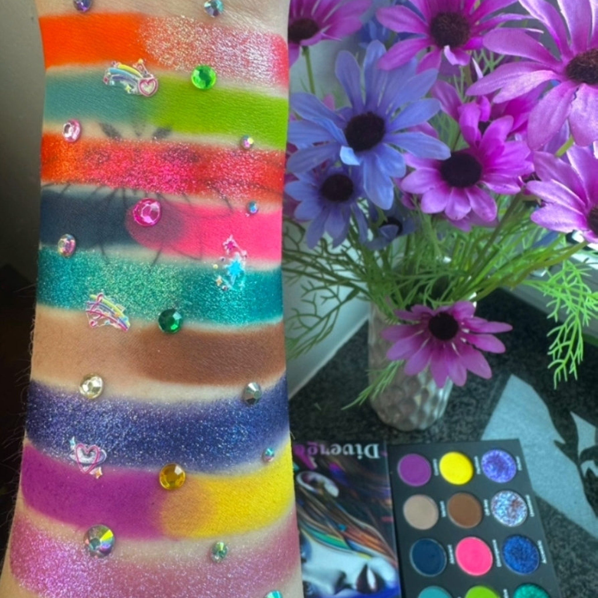 Open Divergence palette showing 12 vibrant powder eyeshadows in matte and shimmer finishes arranged in gradient rows
