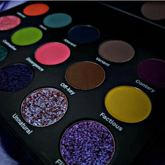 Close-up of shimmering eyeshadow palette showing vibrant teal and bronze pressed pigments with smooth metallic finish