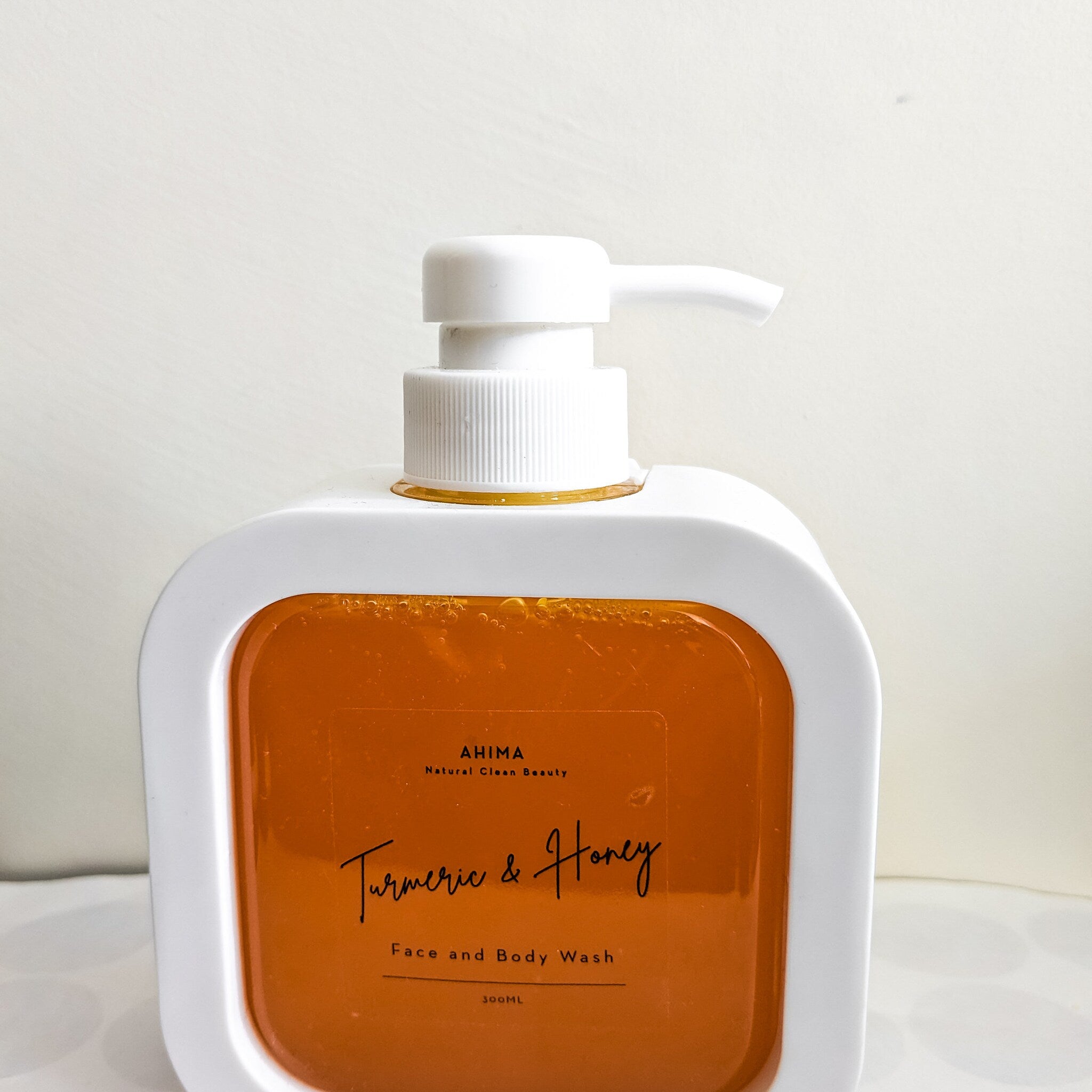 Face and body wash bottle with white plastic, orange liquid, and AHIMA label