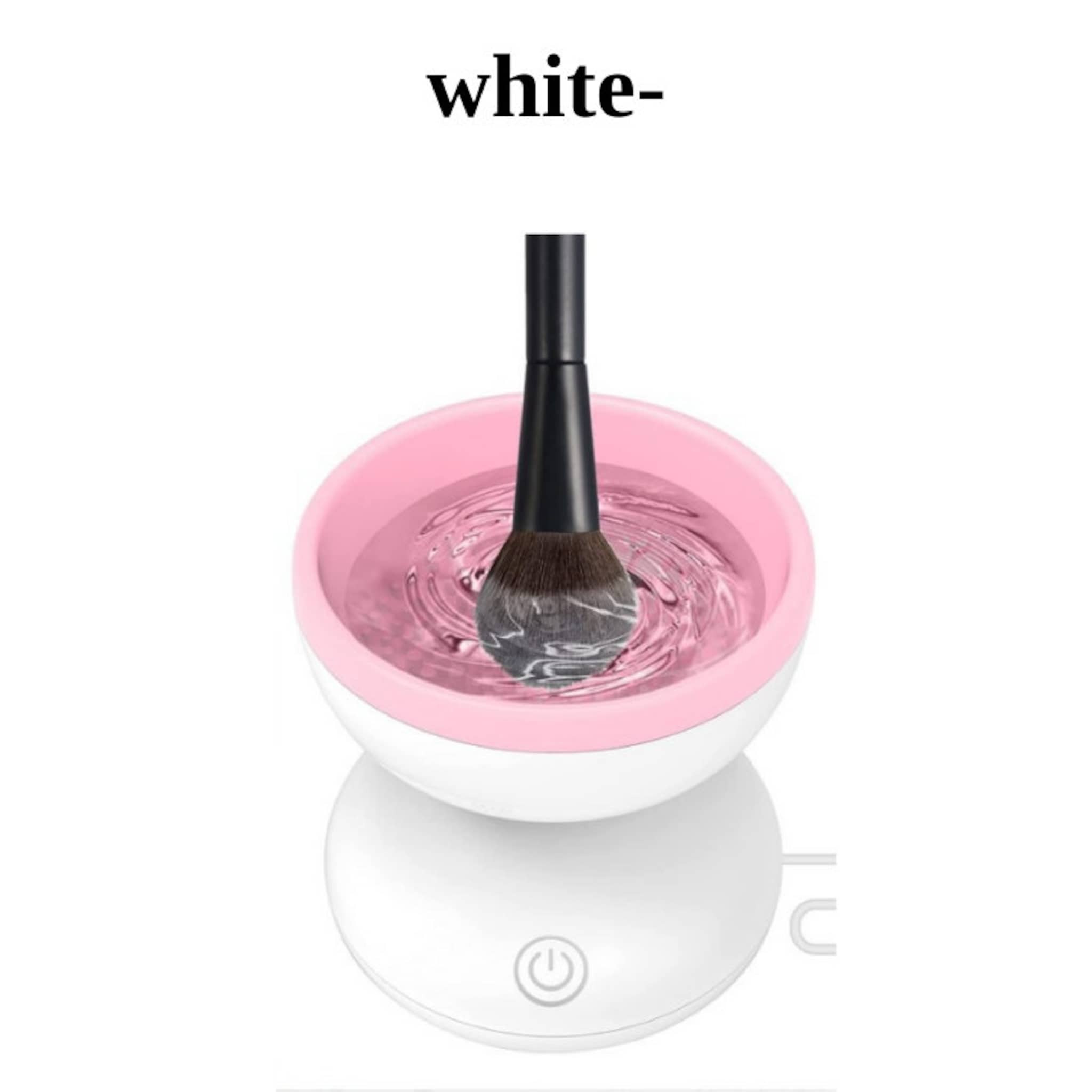 Makeup brush cleaner with pink and white bowl, black brush handle, and water inside
