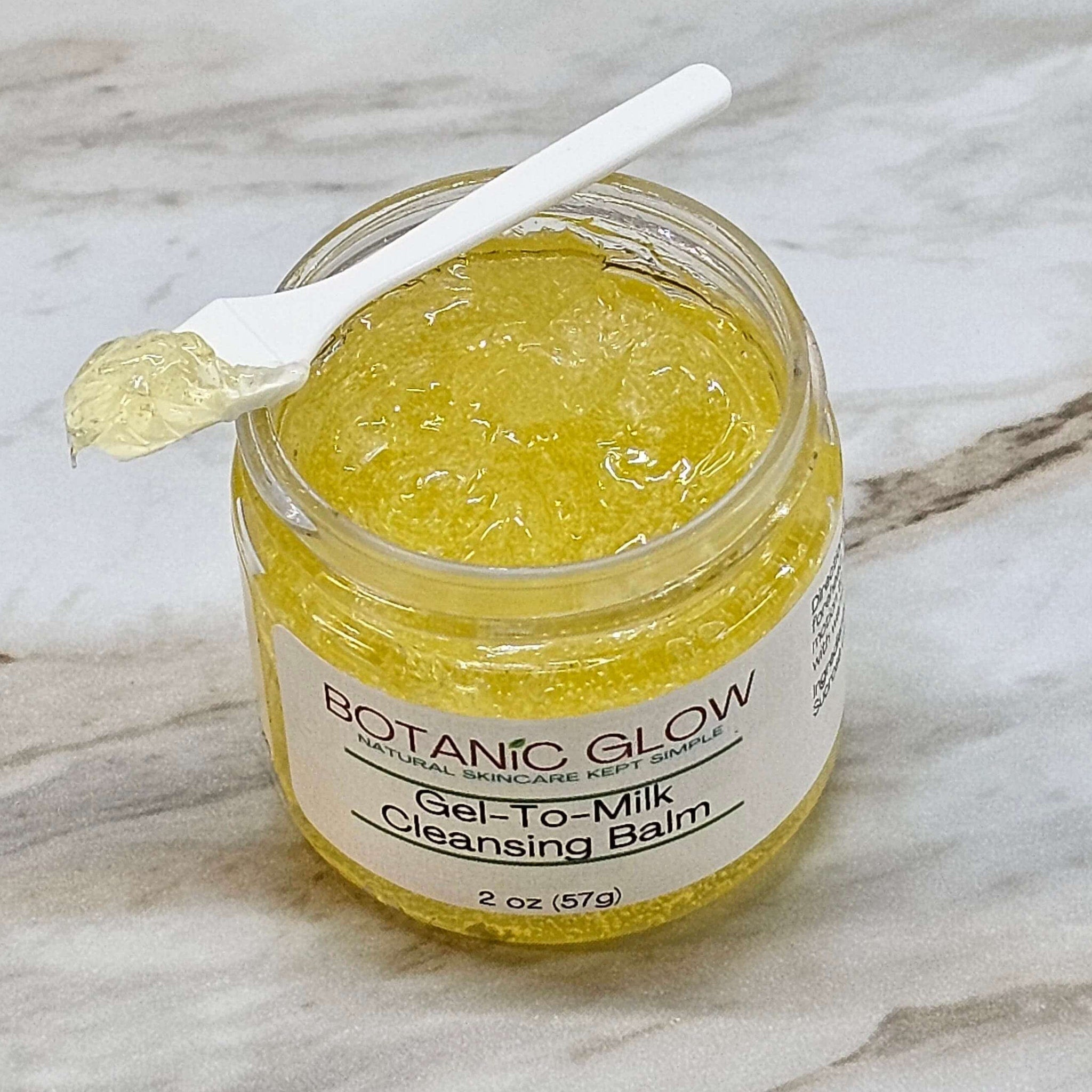 Gel to milk cleansing balm in yellow, clear jar with white spoon, Botanic Glow label visible