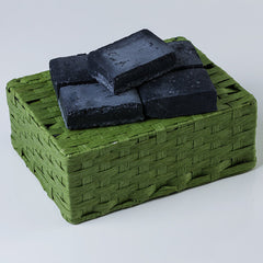 Black soap bars on green woven basket, natural material, square shape