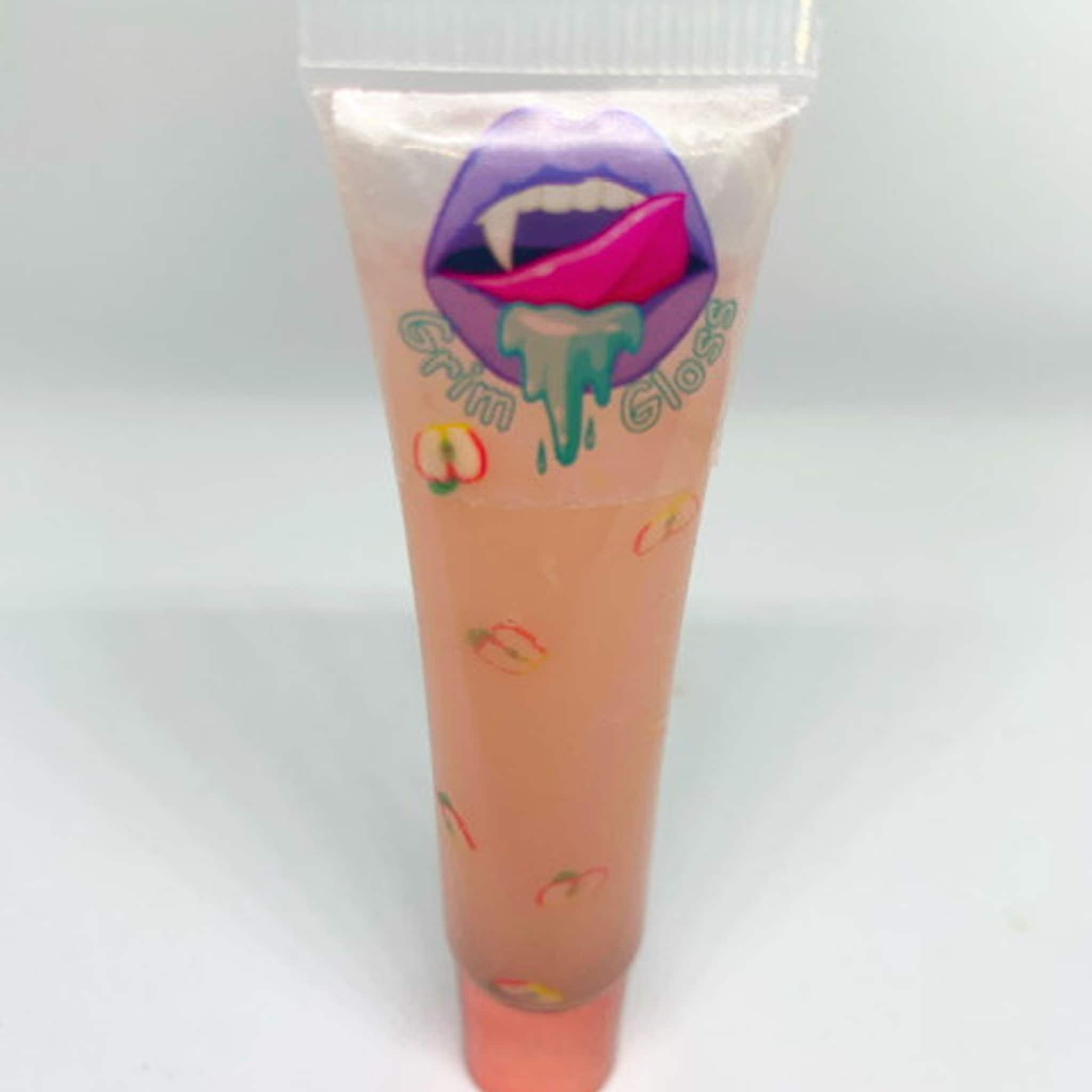 Lip gloss tube with peach color, apple pattern, and Grim Gloss logo on white background