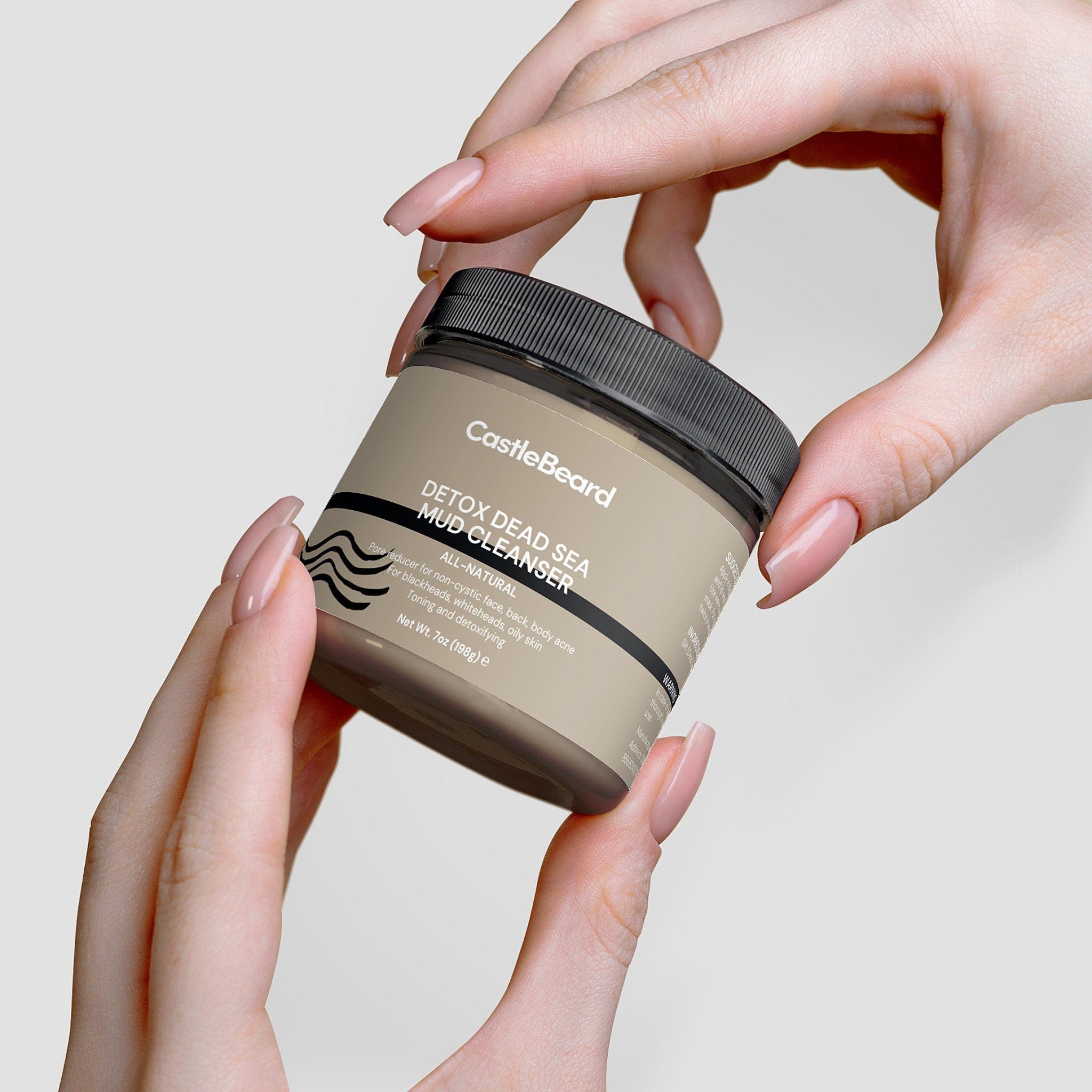 Mud cleanser jar in tan and black held by hands with long nails, CastleBeard brand visible