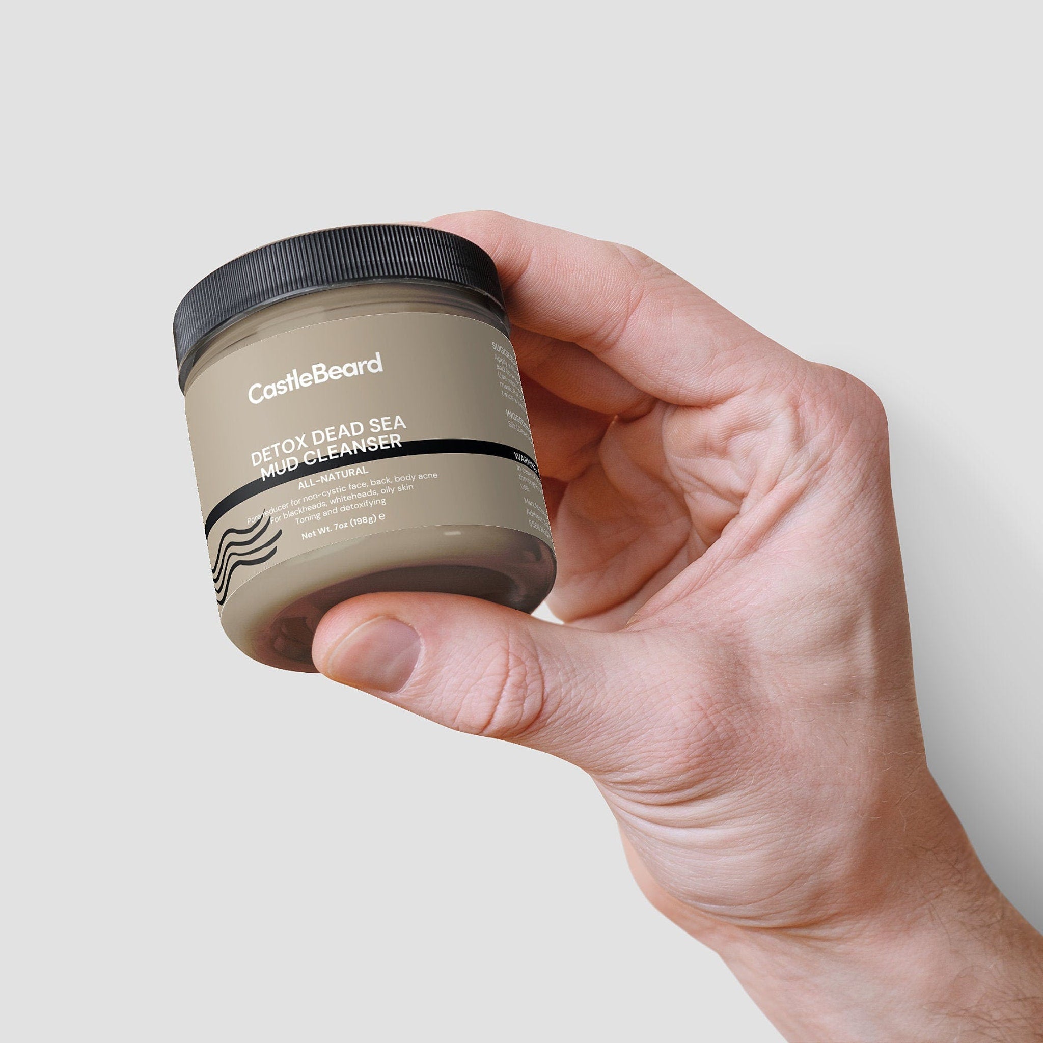 Mud cleanser jar with black lid, tan label, held in hand, CastleBeard branding visible