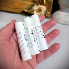 Lip balm tubes, white plastic, "Apple Pie" text, KraftyChickStudios brand, held in hand