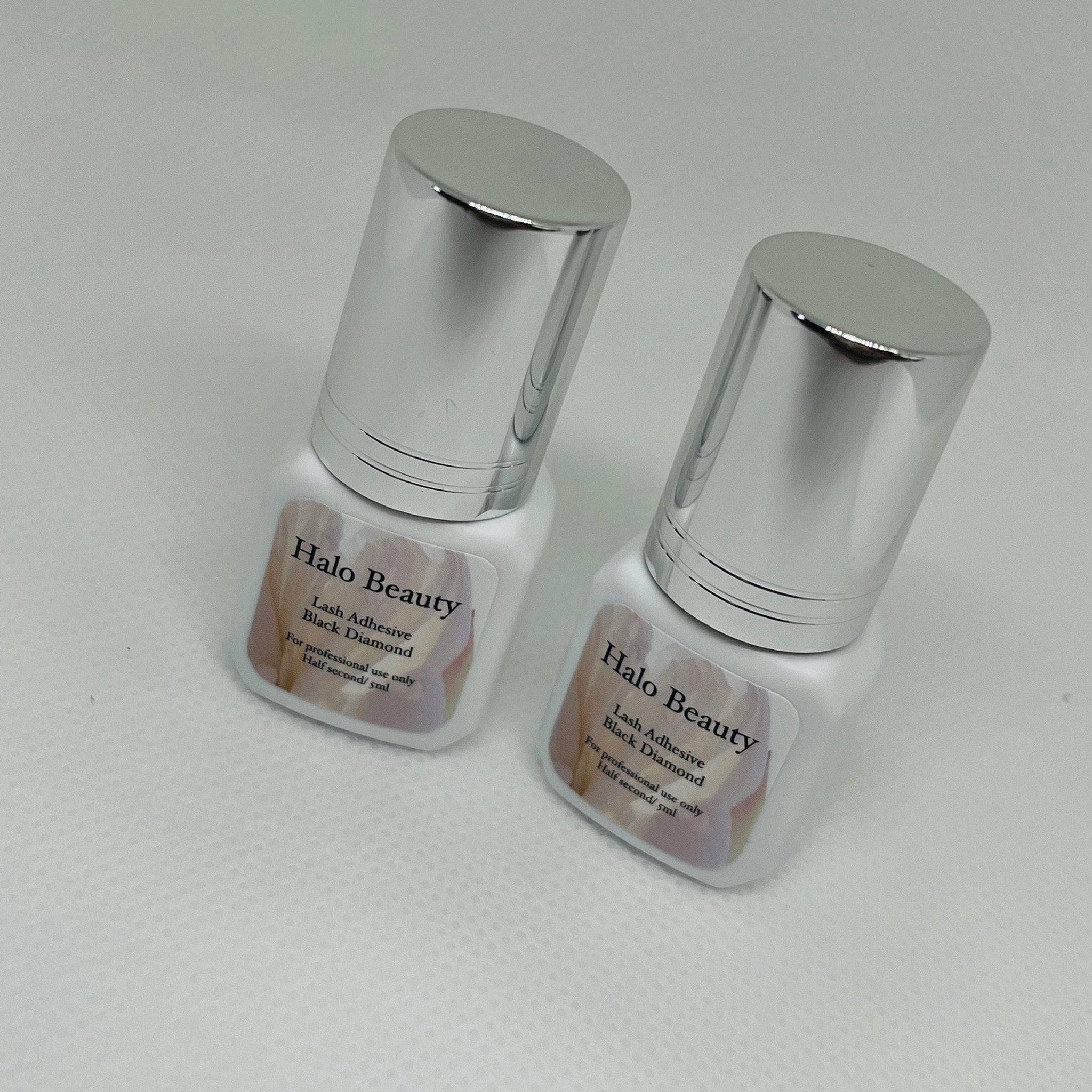 Lash adhesive bottles with silver cap and white bottle, labeled Halo Beauty, for professional use