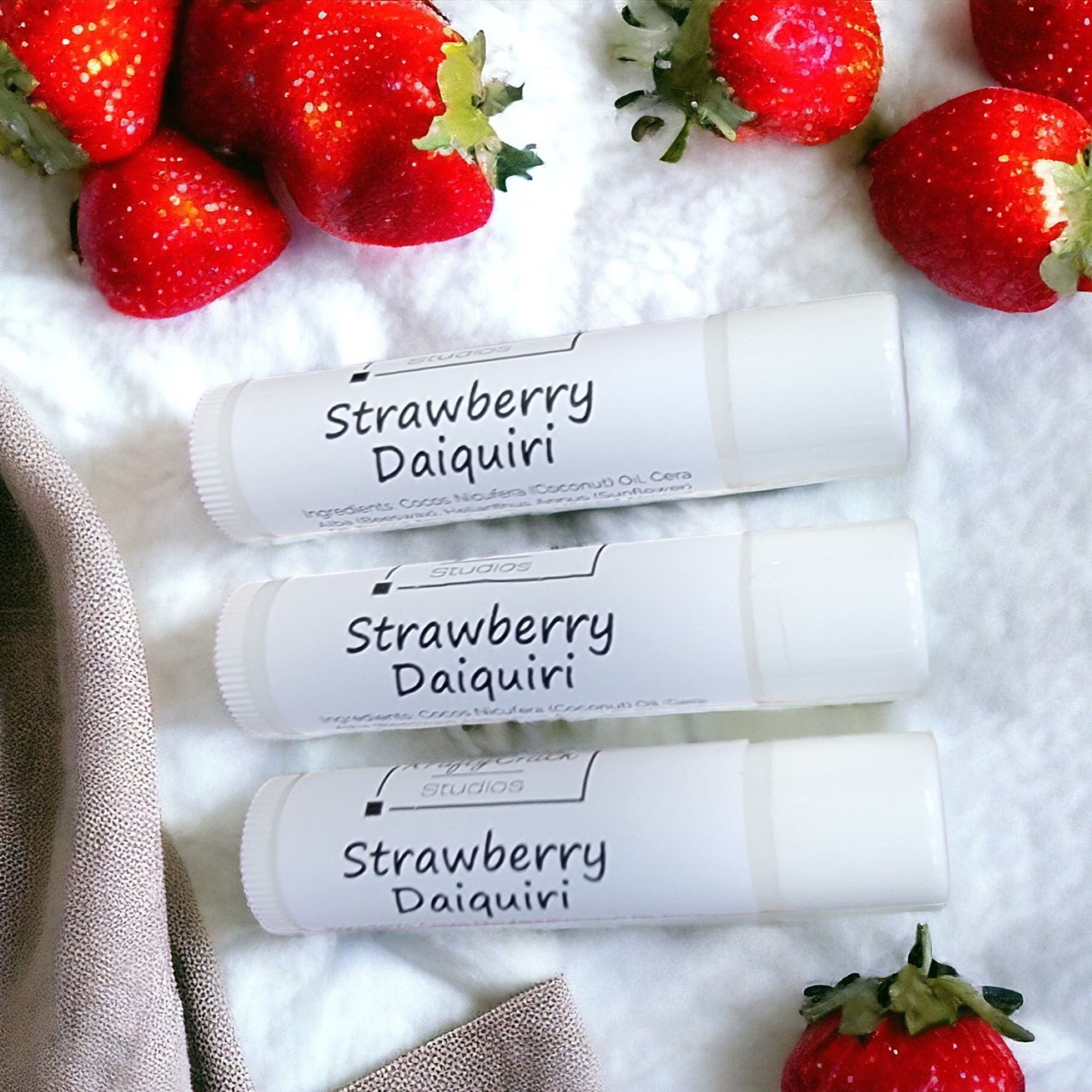 Lip balm tubes, white with black text, KraftyChickStudios Strawberry Daiquiri flavor, with red strawberries