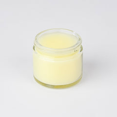 Jar of yellow balm in a clear glass jar, on a white background
