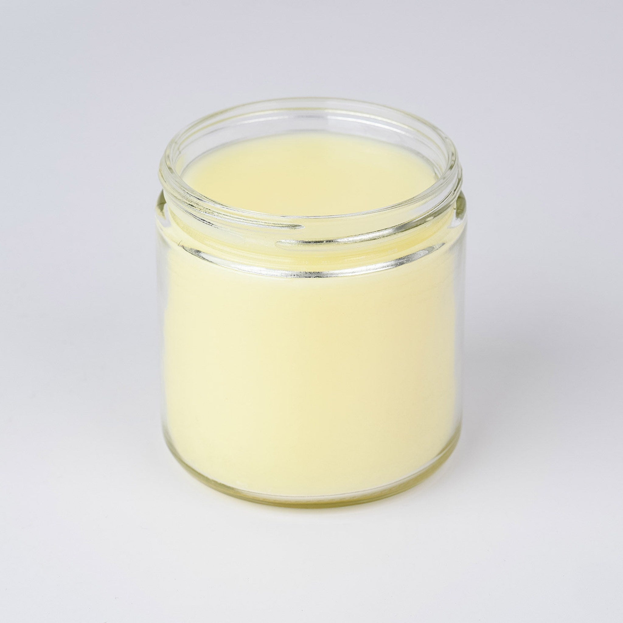 Candle in glass jar with yellow wax and clear glass container