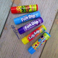 Lip balm tubes in various colors with brand names on a wooden surface.