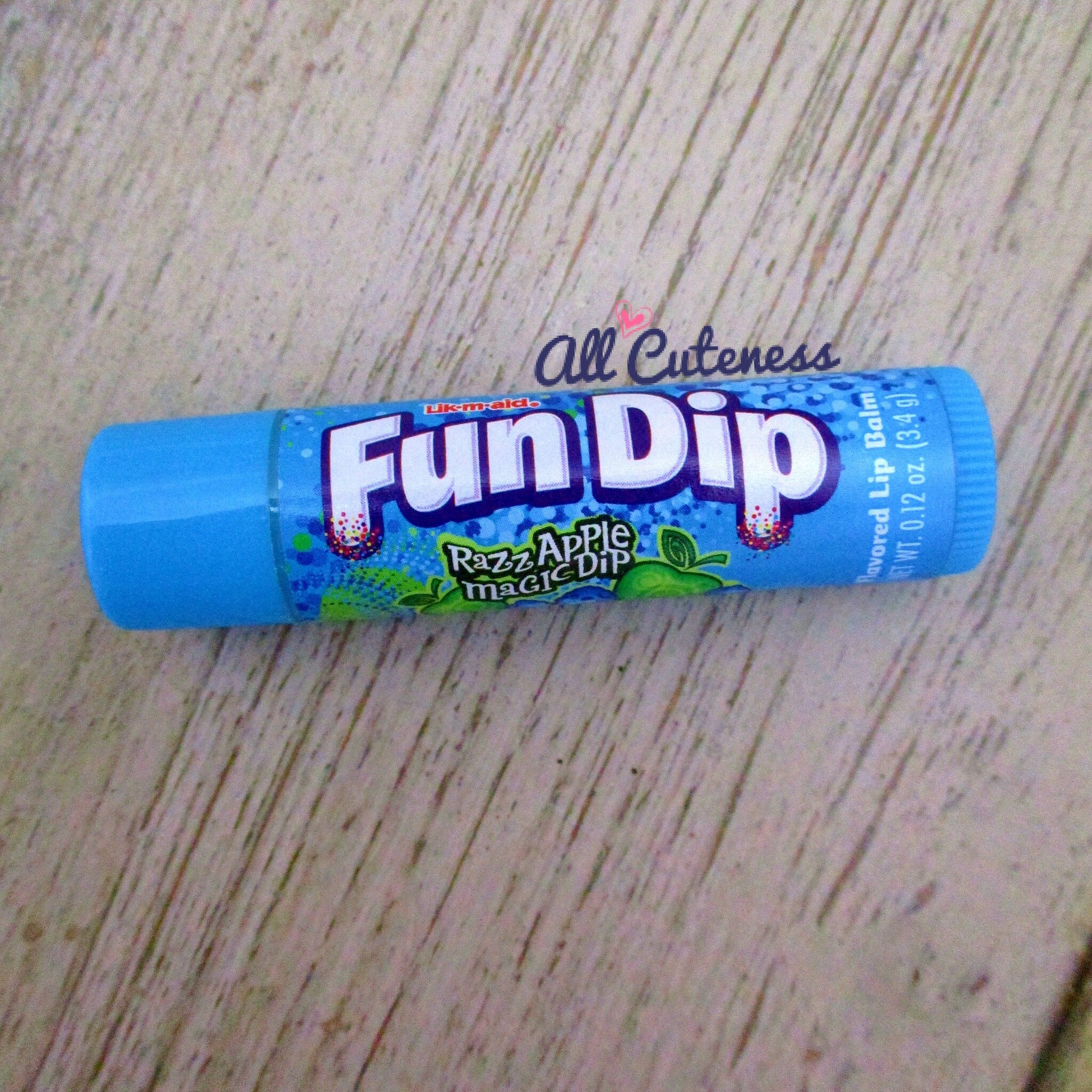 Lip balm tube with blue, white, and green graphics, "Fun Dip" text, and Razz Apple Magic Dip flavor