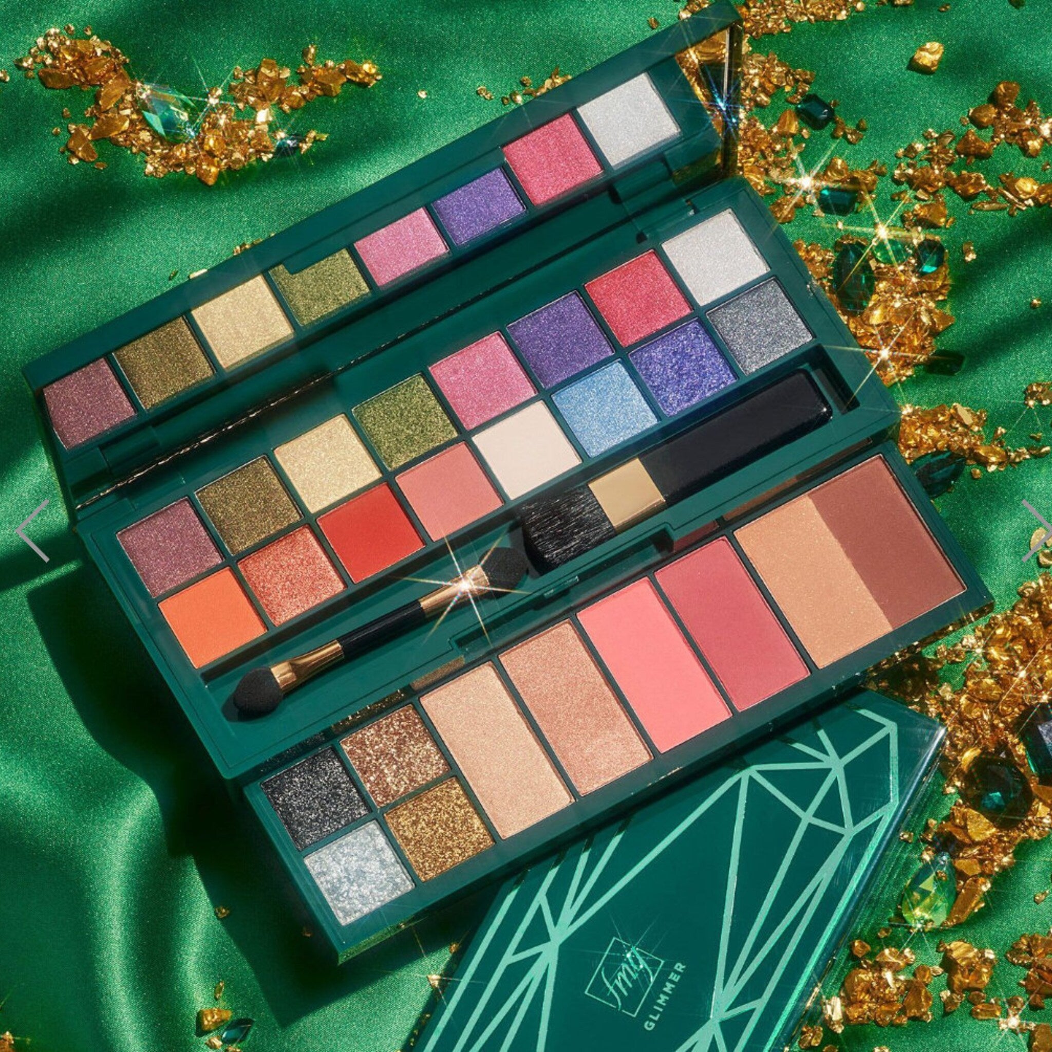 Eyeshadow palette with multiple colors, green case, and makeup brushes, "fmGlimmer" text visible