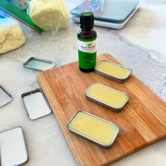 Lip balm tins with yellow balm on a wooden board, Plant Therapy essential oil bottle