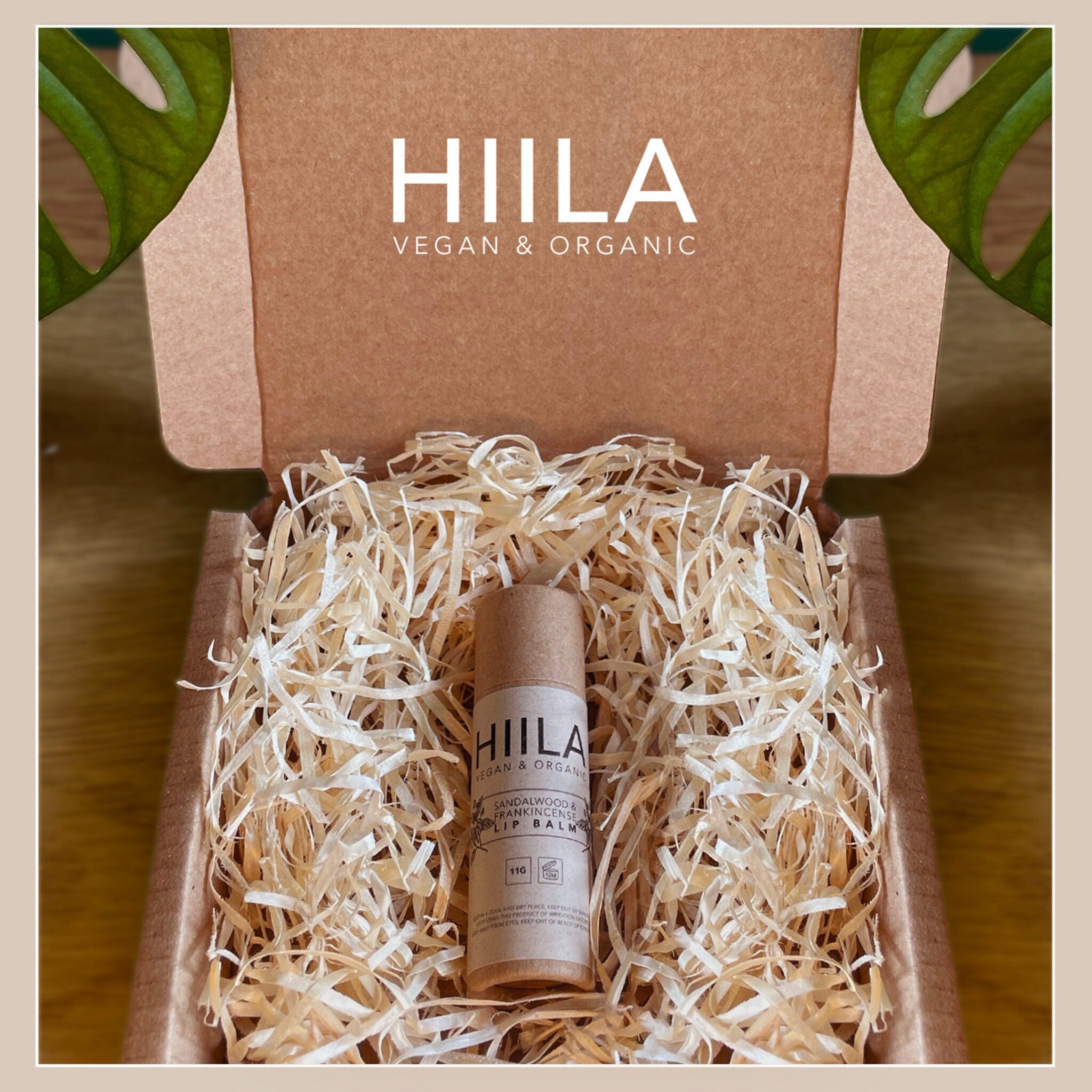 Lip balm tube in cardboard packaging with wood shavings, HIILA branding visible
