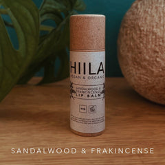 Lip balm tube with brown cap and HIILA label, on wooden surface