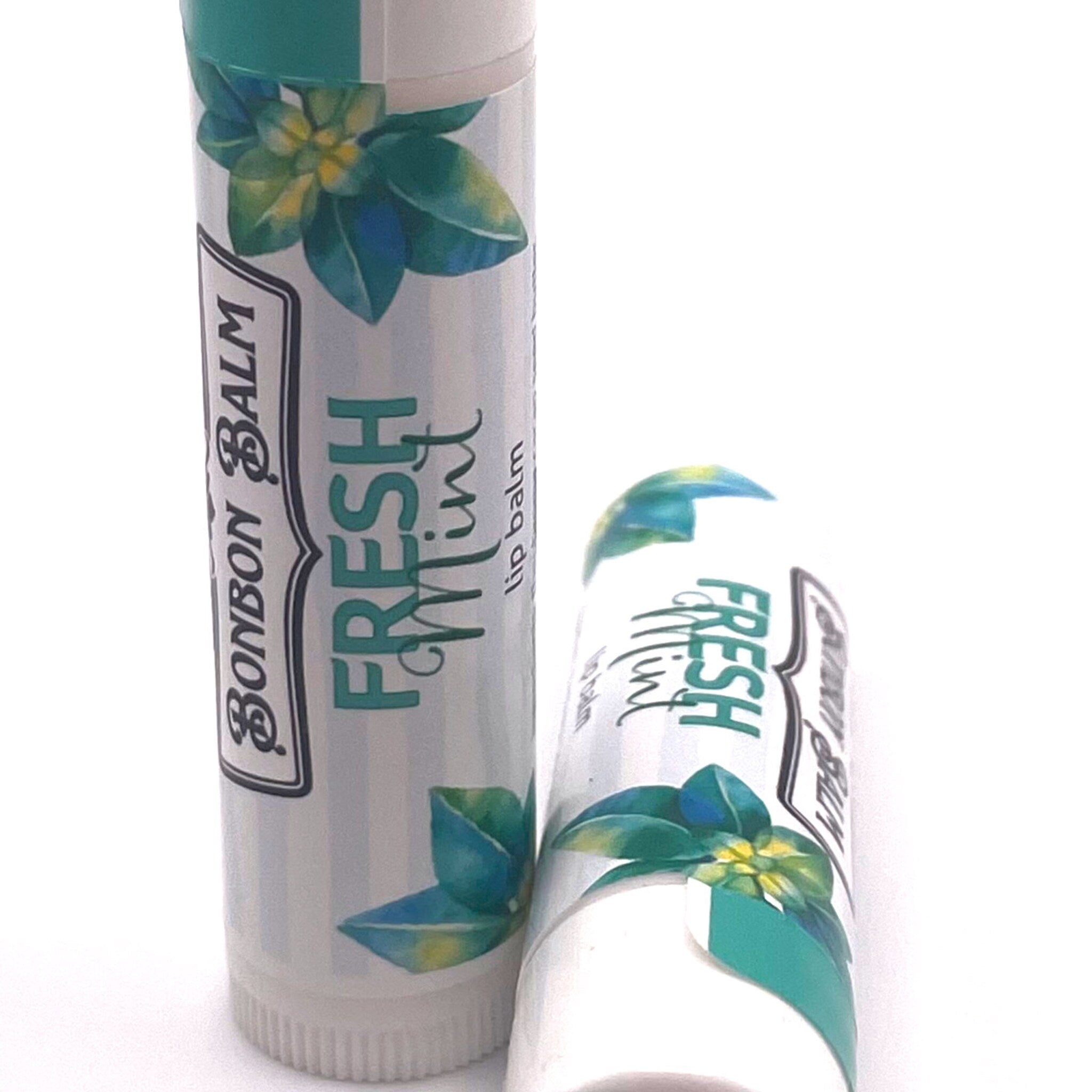 Lip balm tubes with white, teal, and green floral design, "Fresh Mint" text, and "Bonbon Balm" label
