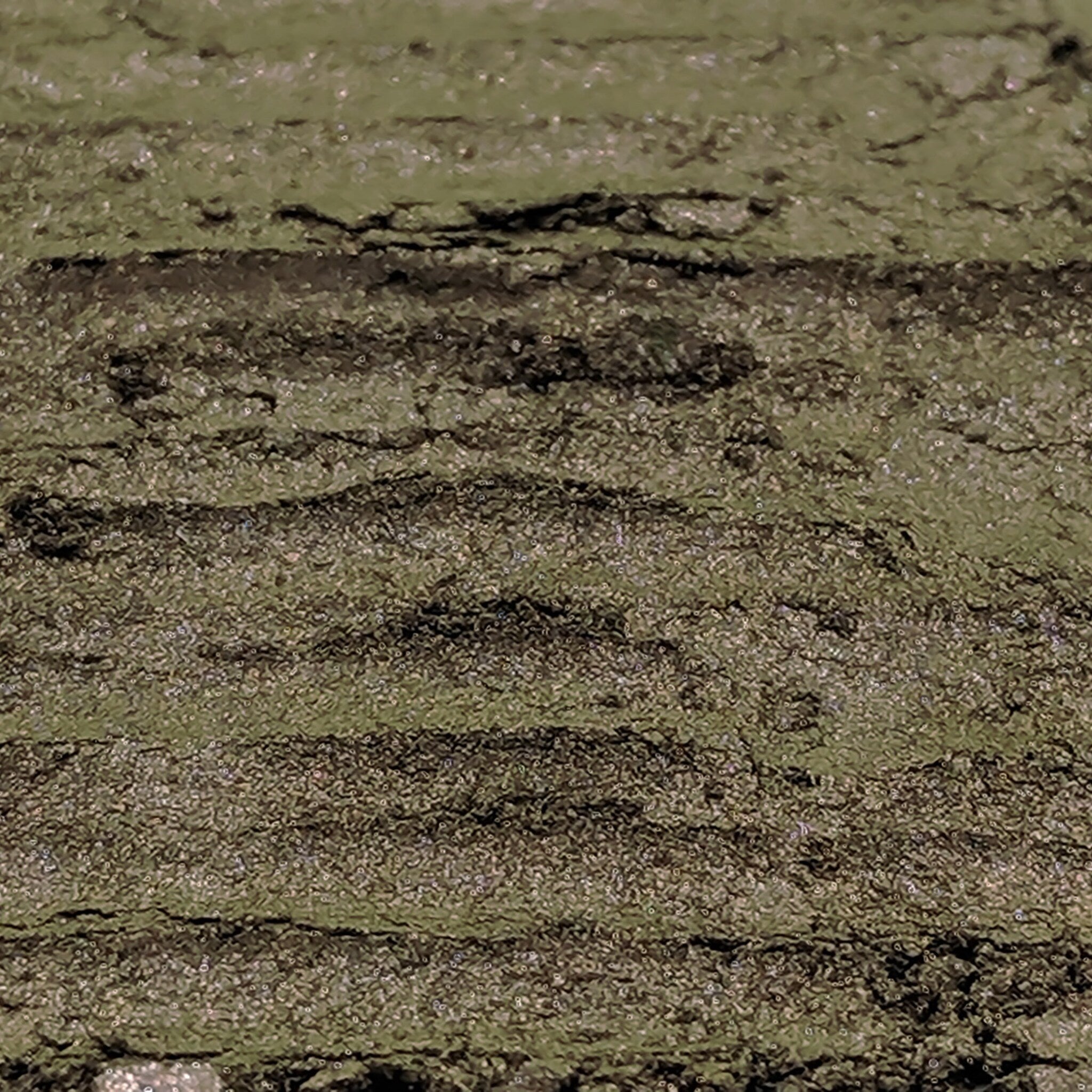 Hand applying shimmering deep olive green and copper duochrome loose powder eyeshadow with fingertip