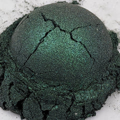 Side view of deep emerald green shimmer loose powder eyeshadow with duochrome effect in open jar