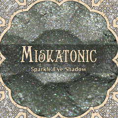 Eye makeup shimmer shadow, grey with sparkle, MISKATONIC brand name visible in ornate frame