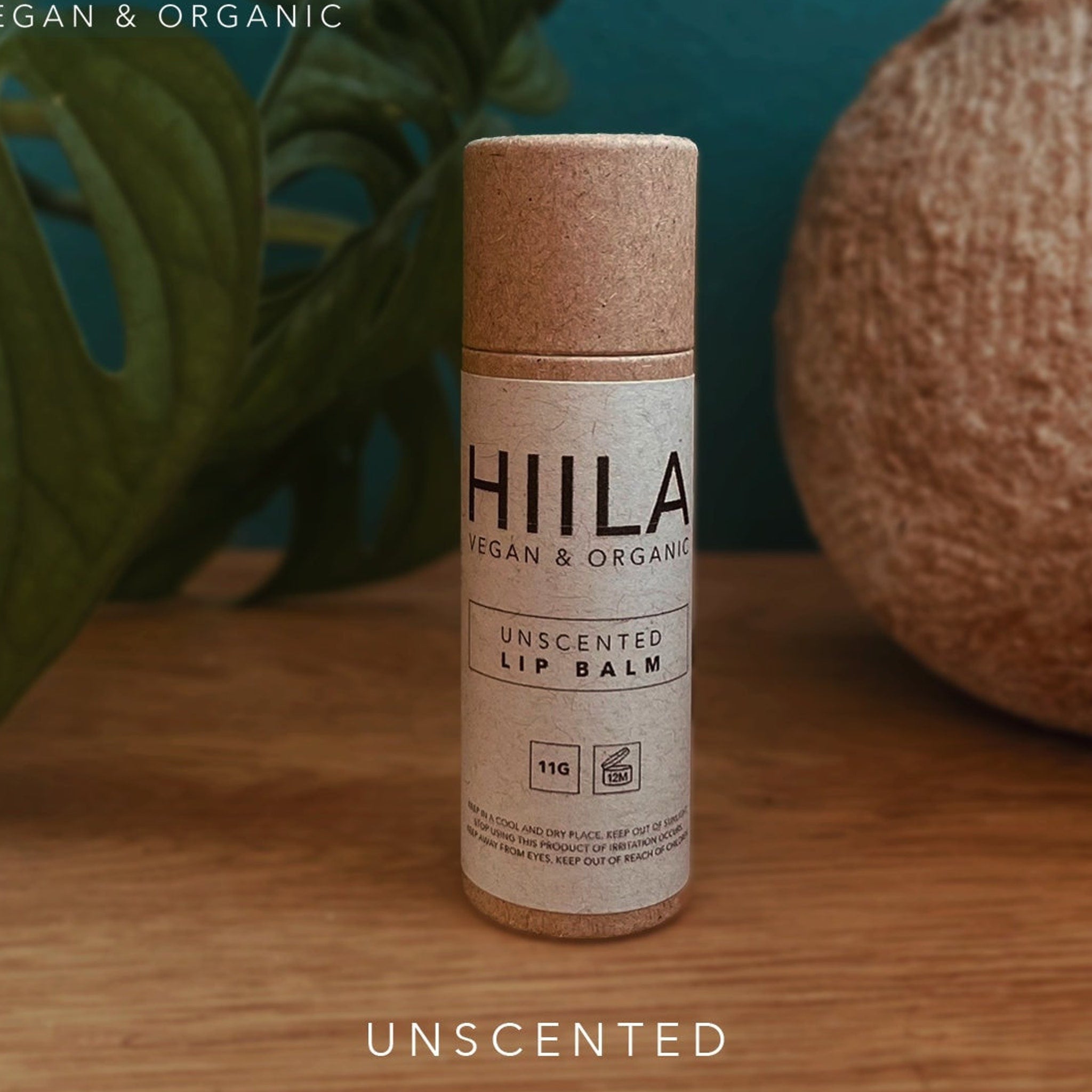 Lip balm tube with brown cap and HIILA label, unscented, on a wooden surface