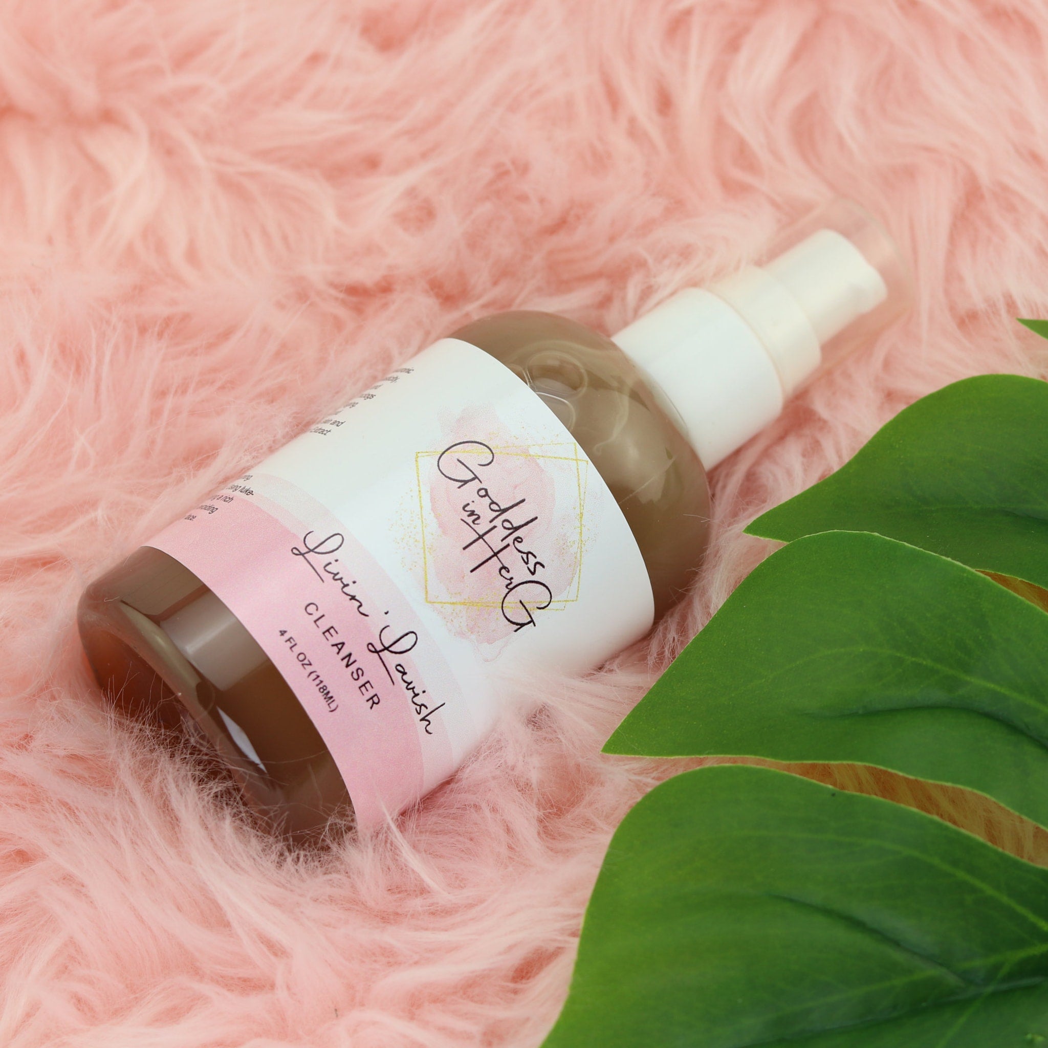 Cleanser bottle with clear liquid, white pump, and pink label on pink fur background
