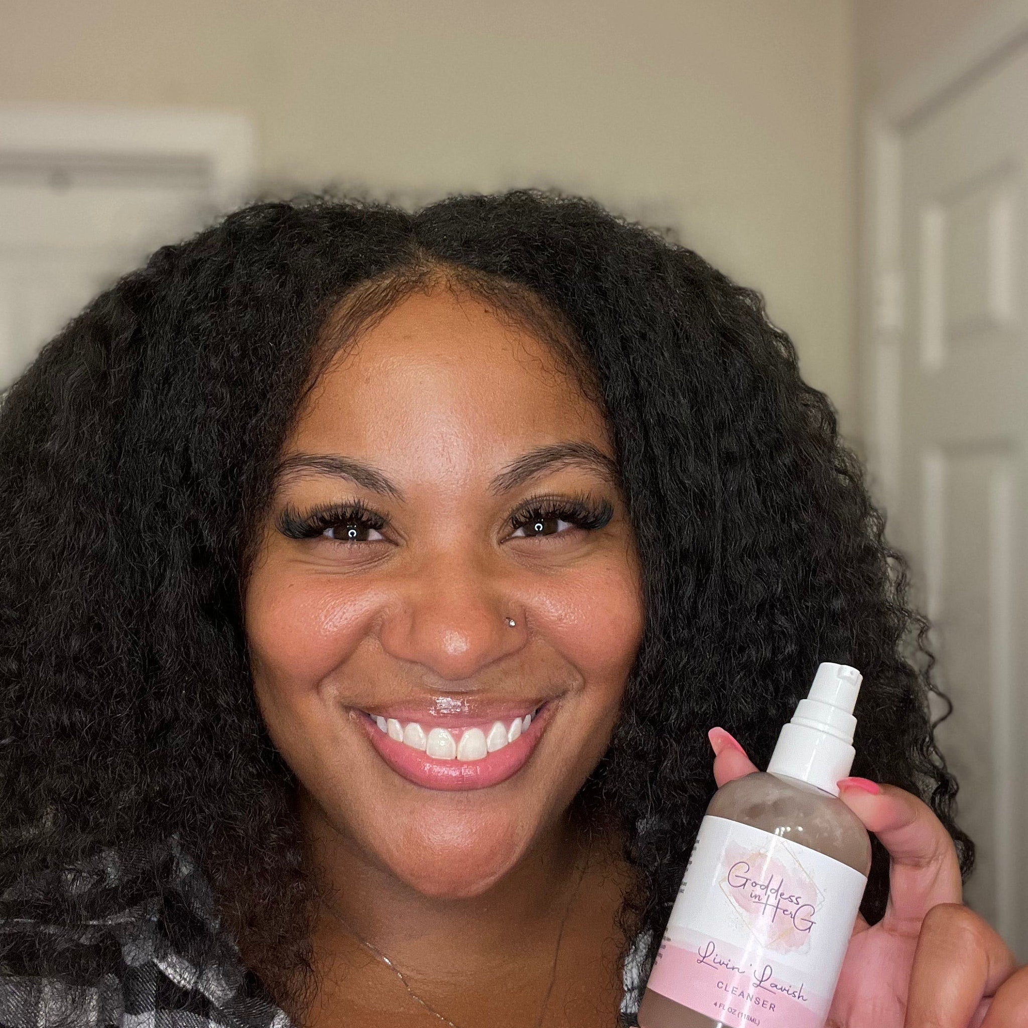 Cleanser bottle held by smiling woman with black curly hair, pink nails and "Goddess in Her G" text