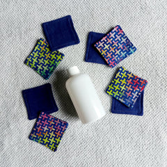 Makeup remover pads, navy blue and geometric patterned fabric pads, with a white bottle on a towel