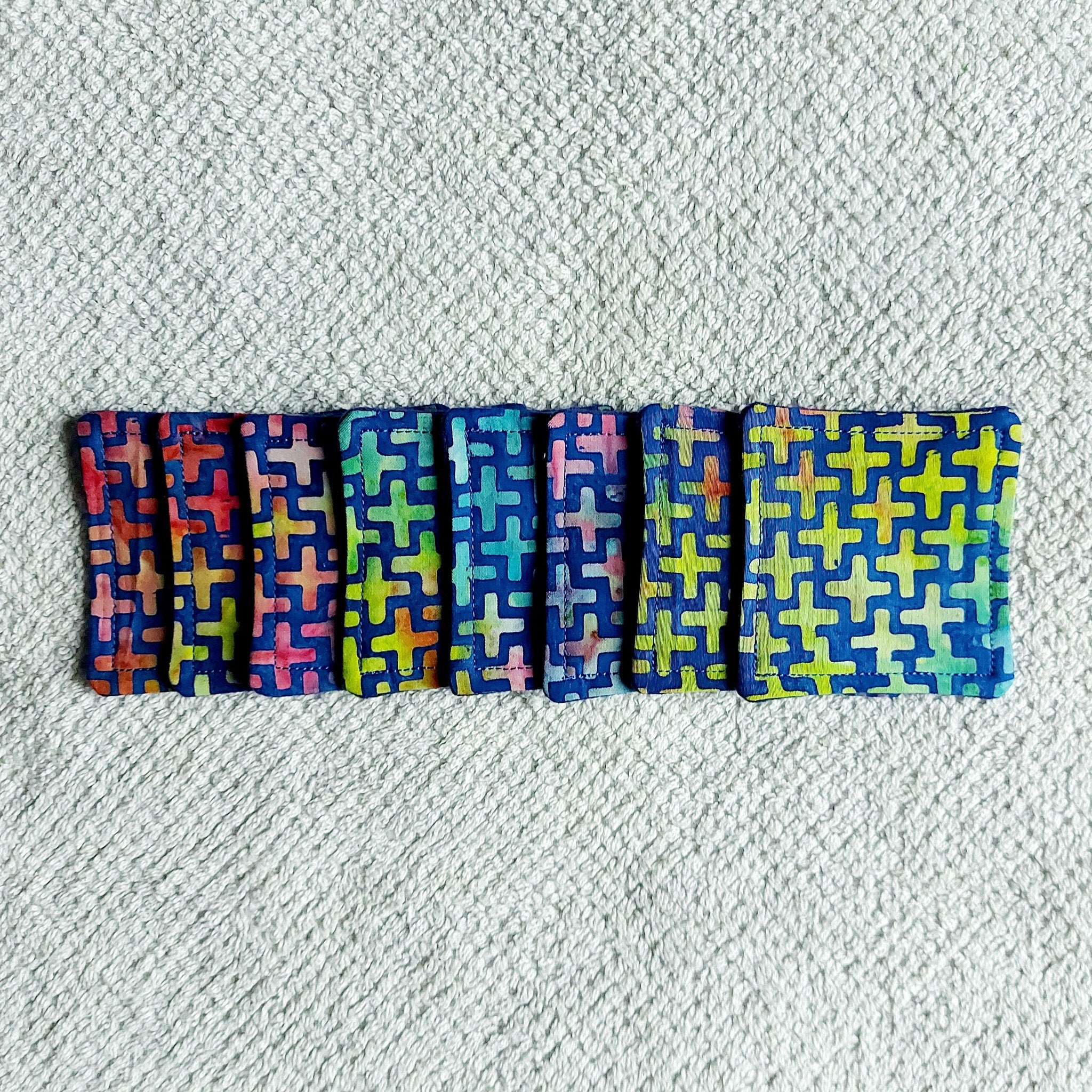 Cloth coasters with cross pattern in blue, red, green, and yellow on white towel