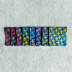 Cloth coasters with cross pattern in blue, red, green, and yellow on white towel