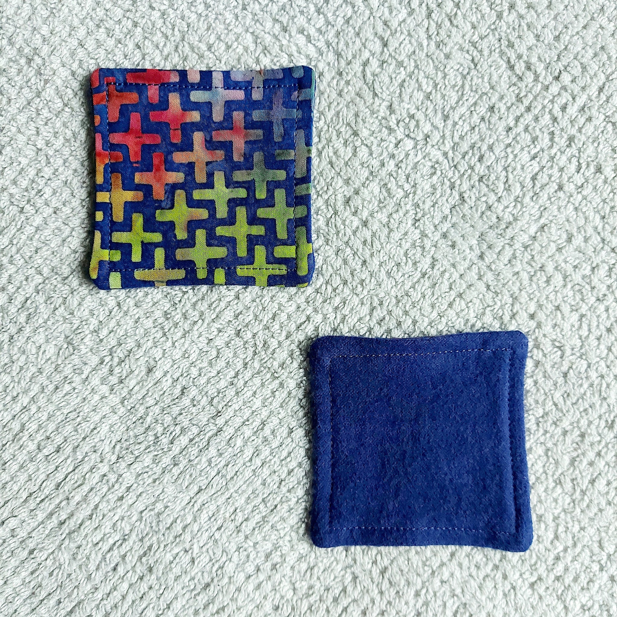 Coasters, blue felt and patterned fabric squares on white textured surface