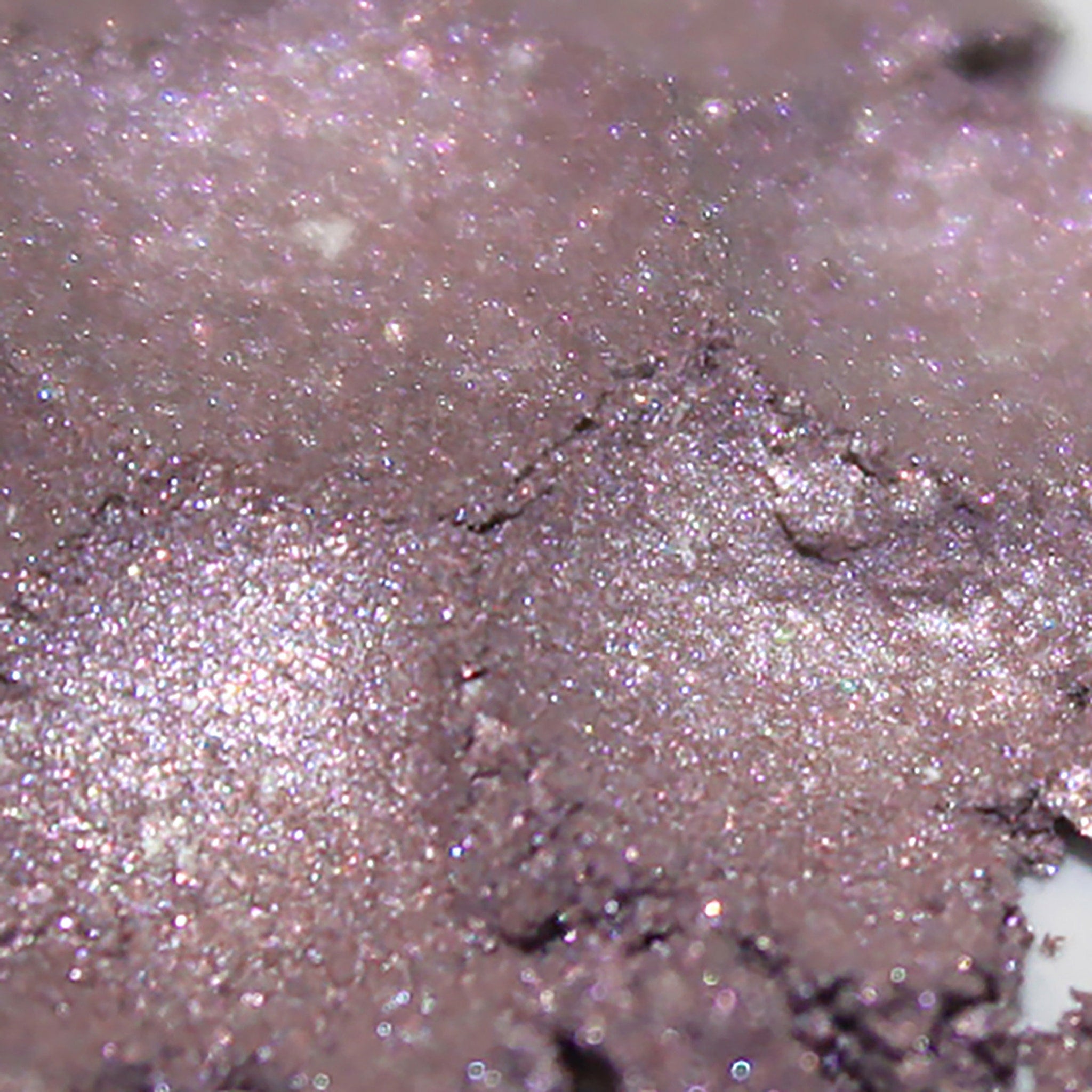 Eyeshadow, shimmering mauve powder with glitter particles and cracked texture