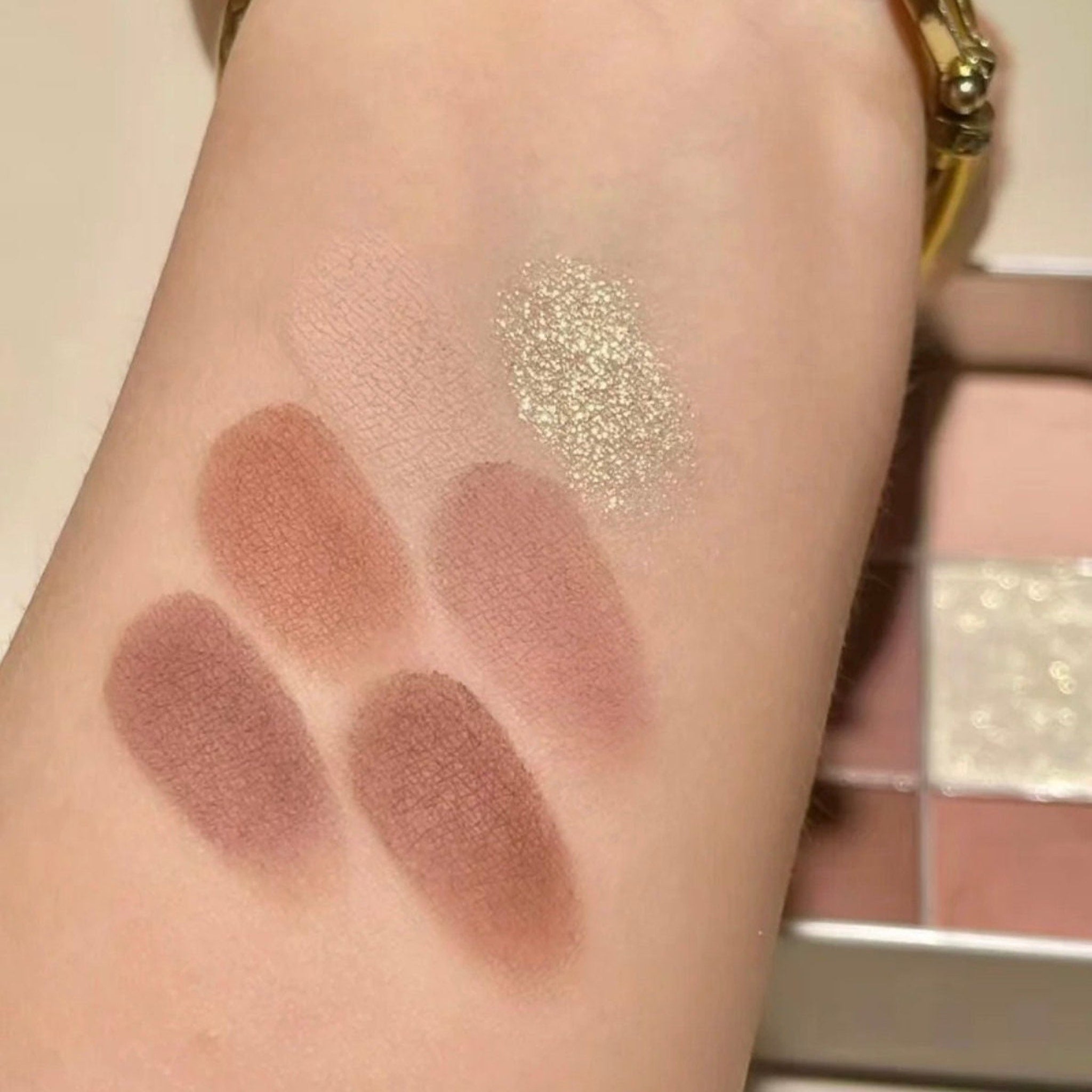 Close-up of pastel pink and lavender eyeshadows with shimmer finish in a sleek rectangular palette