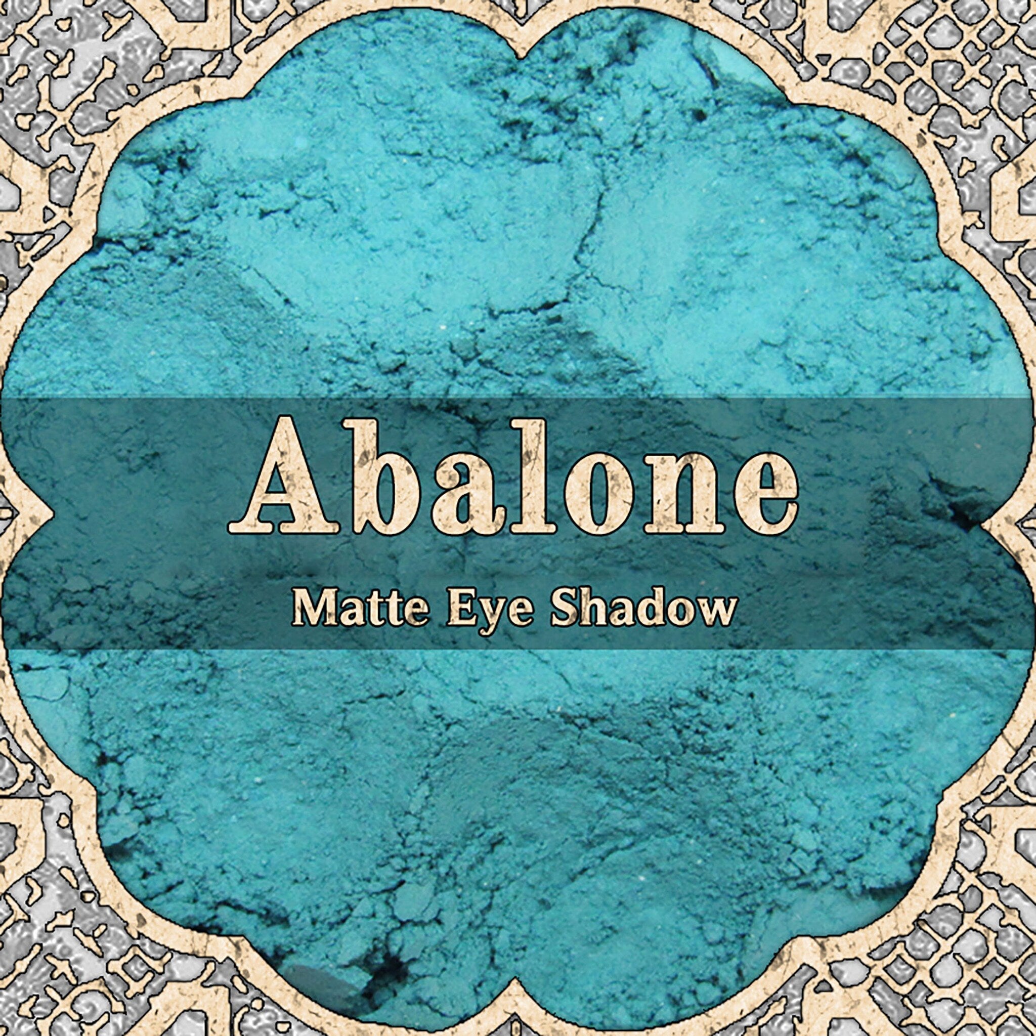 Light turquoise matte loose powder eyeshadow in a small round jar with black lid, pastel aqua color visible