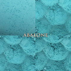 Side view of pastel aqua vegan loose powder eyeshadow in matte finish with mermaid-themed packaging