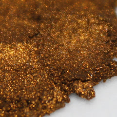 Side view of loose metallic orange gold eye shadow powder in steampunk-inspired packaging with intricate brass details