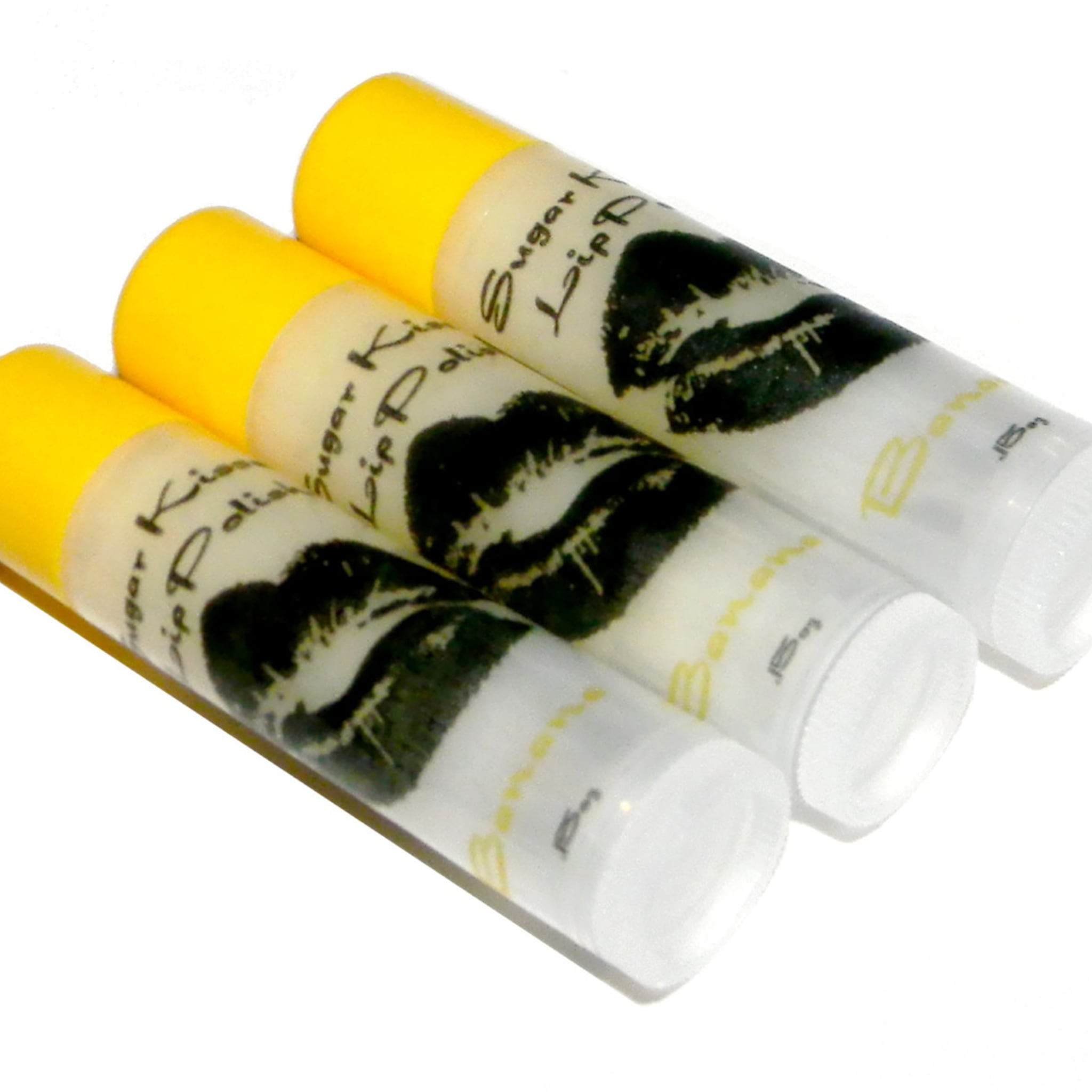 Lip scrub tubes with yellow caps, white labels, and black lip print, BANANA brand visible