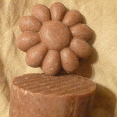 Brown flower-shaped soap with textured surface and a rectangular base against a tan background