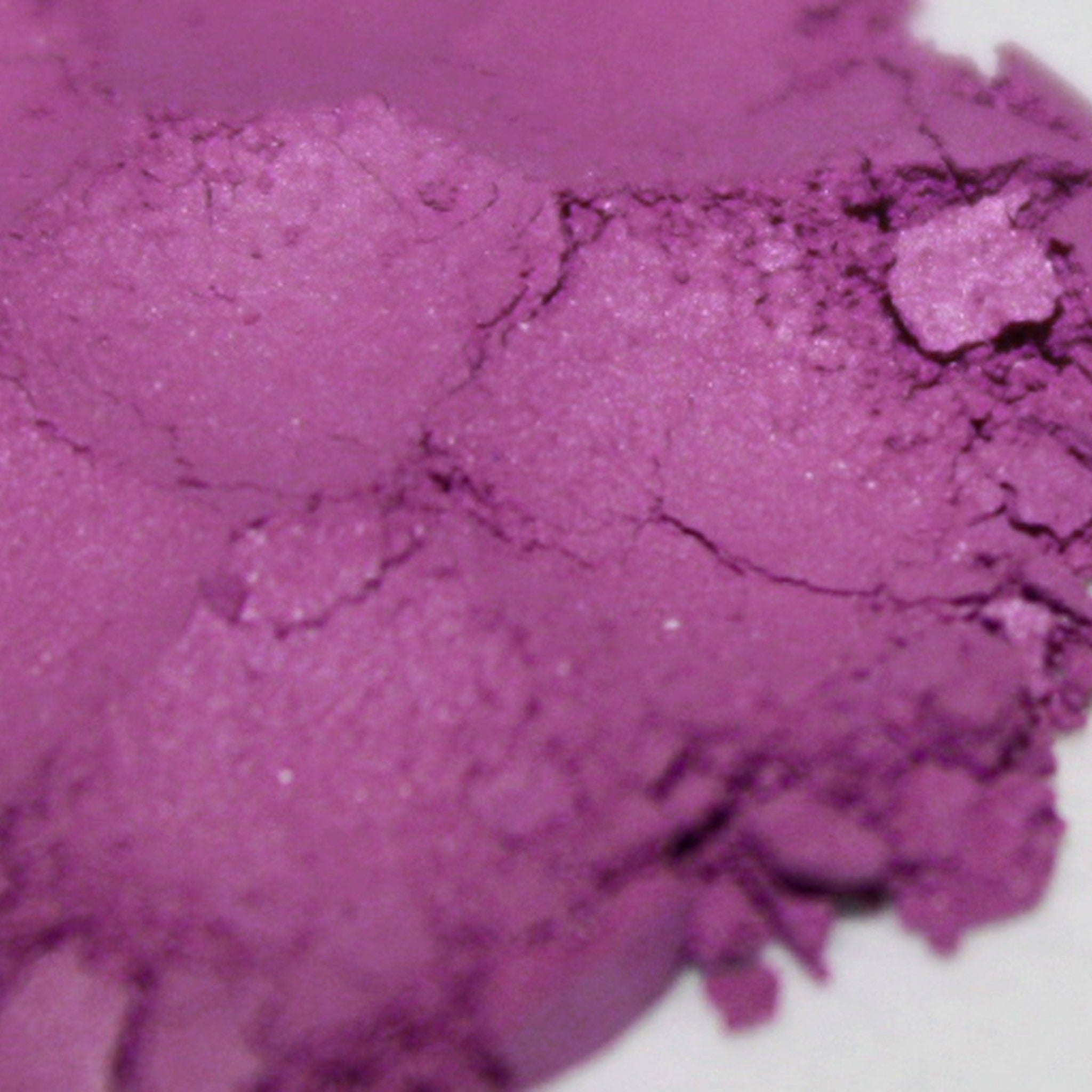 Side view of loose powder eyeshadow jar showing vibrant orchid and magenta pigments with matte finish