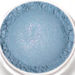 Side view of vegan mineral eyeshadow pot showing blue base with pink and turquoise shimmer particles catching light.